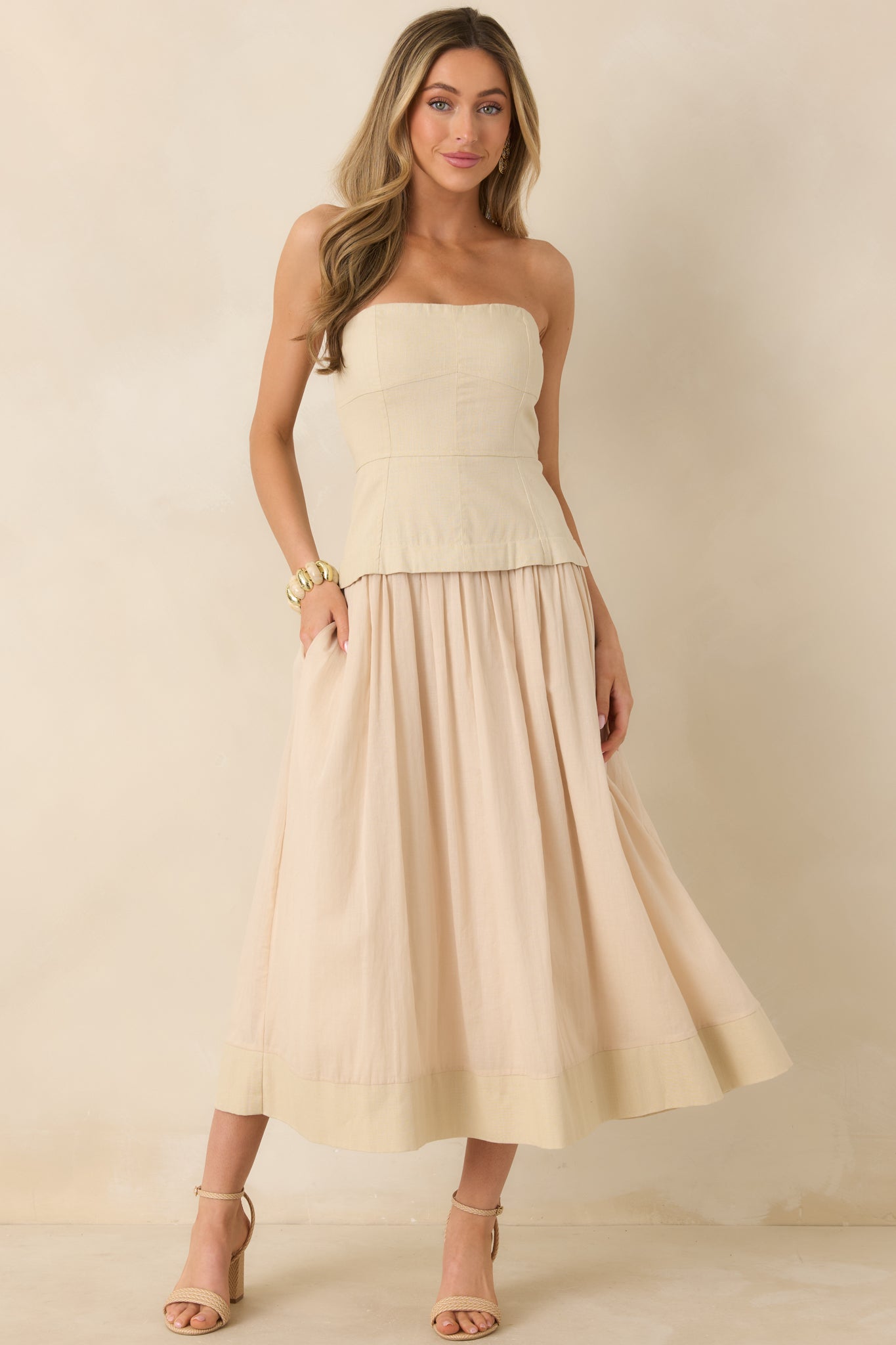 Front view of midi dress featuring smooth beige fabric, full lining, and functional pockets.