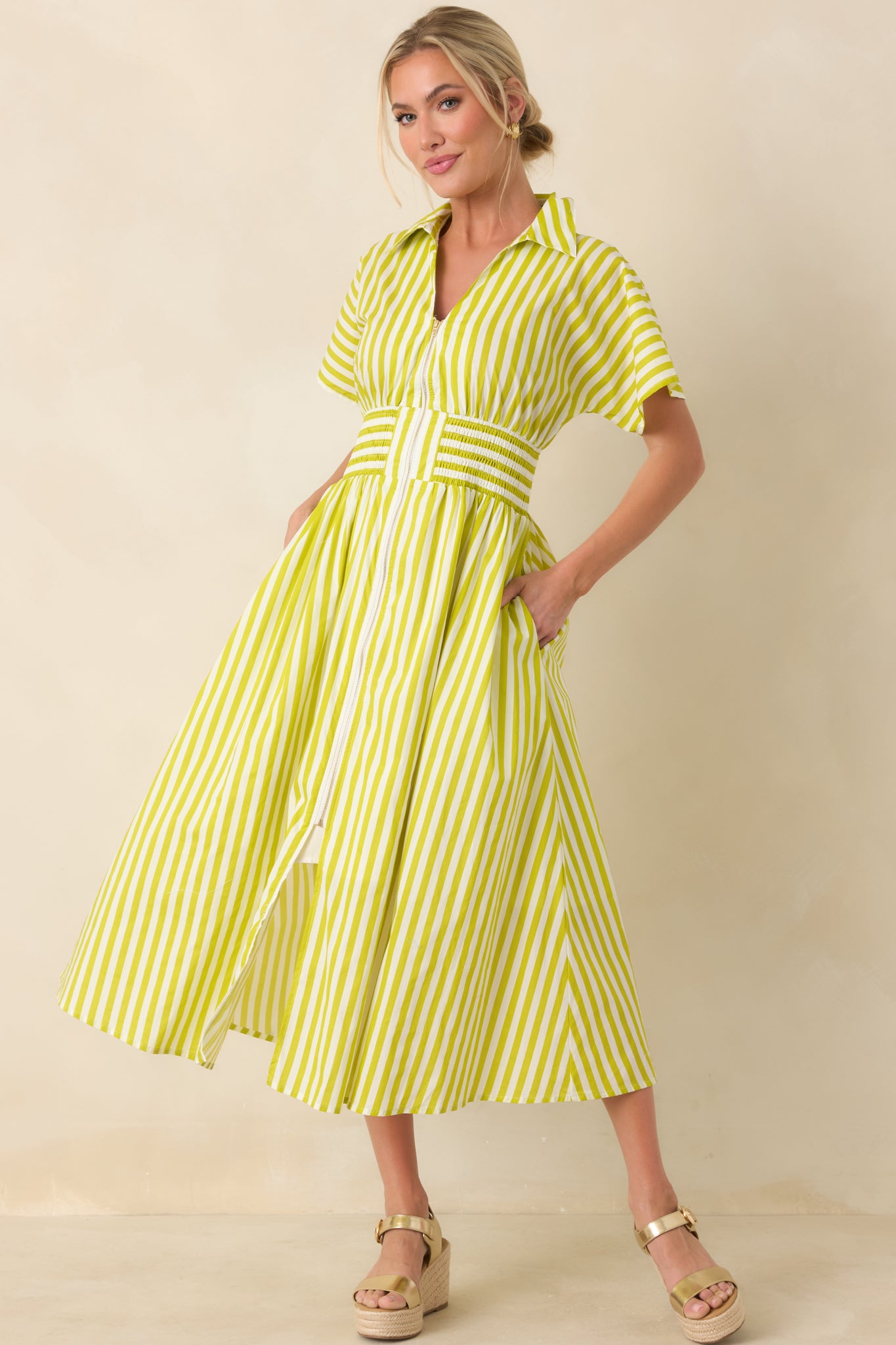 Striped green and white midi dress with a collared neckline, short sleeves, and pockets, designed with a fitted smocked waist and full skirt.
