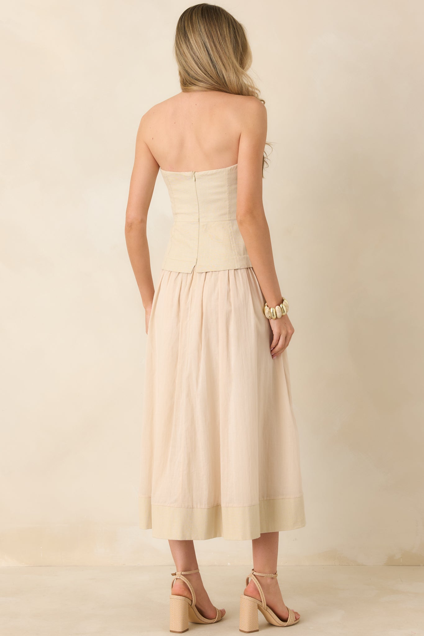 Back view of beige midi dress showing concealed back zipper closure, adjustable straps, and flowing skirt.
