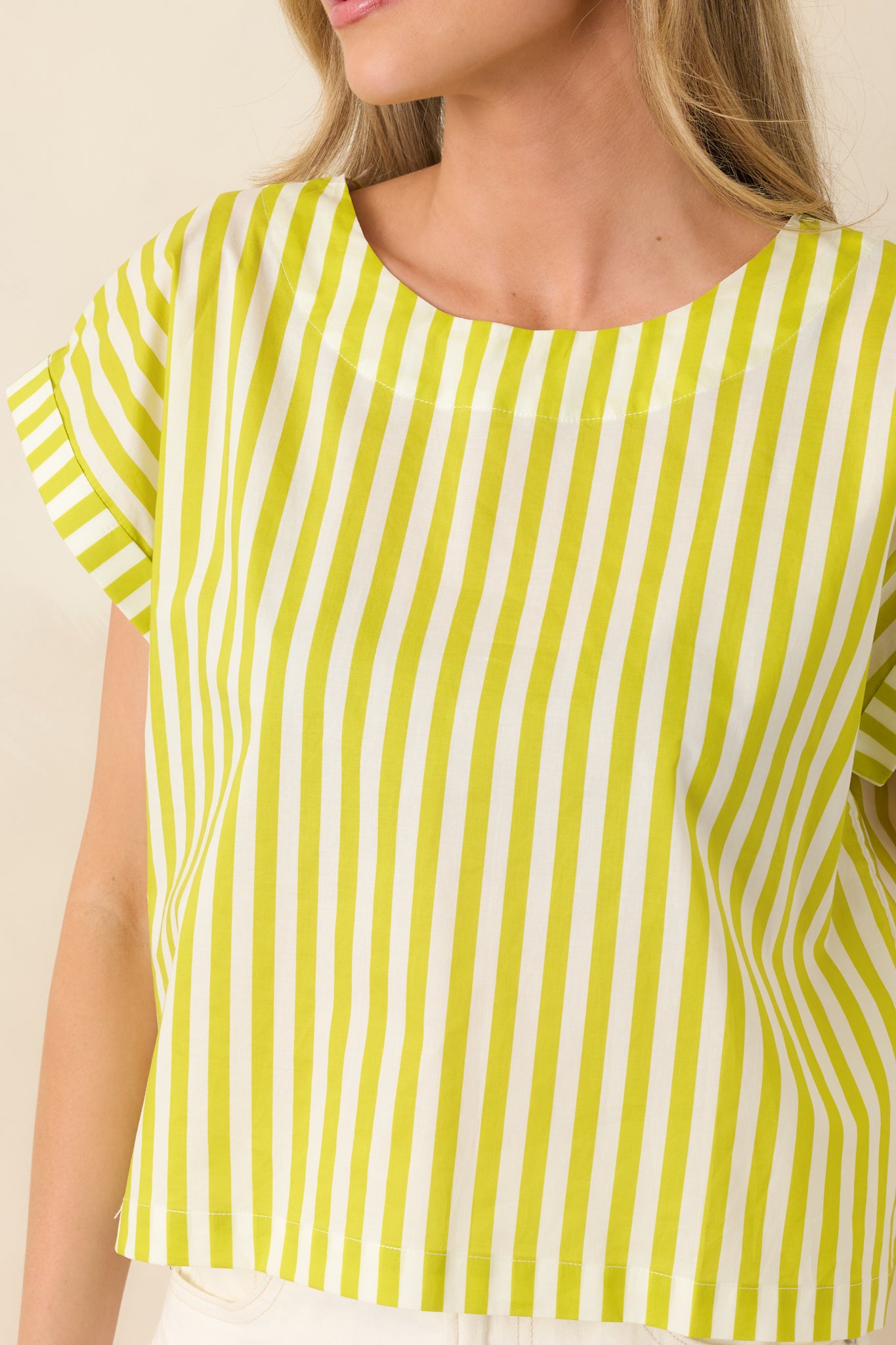 Close-up of the green cotton fabric revealing the vertical stripe detailing, structured neckline finish, and crisp sleeve cuffs.