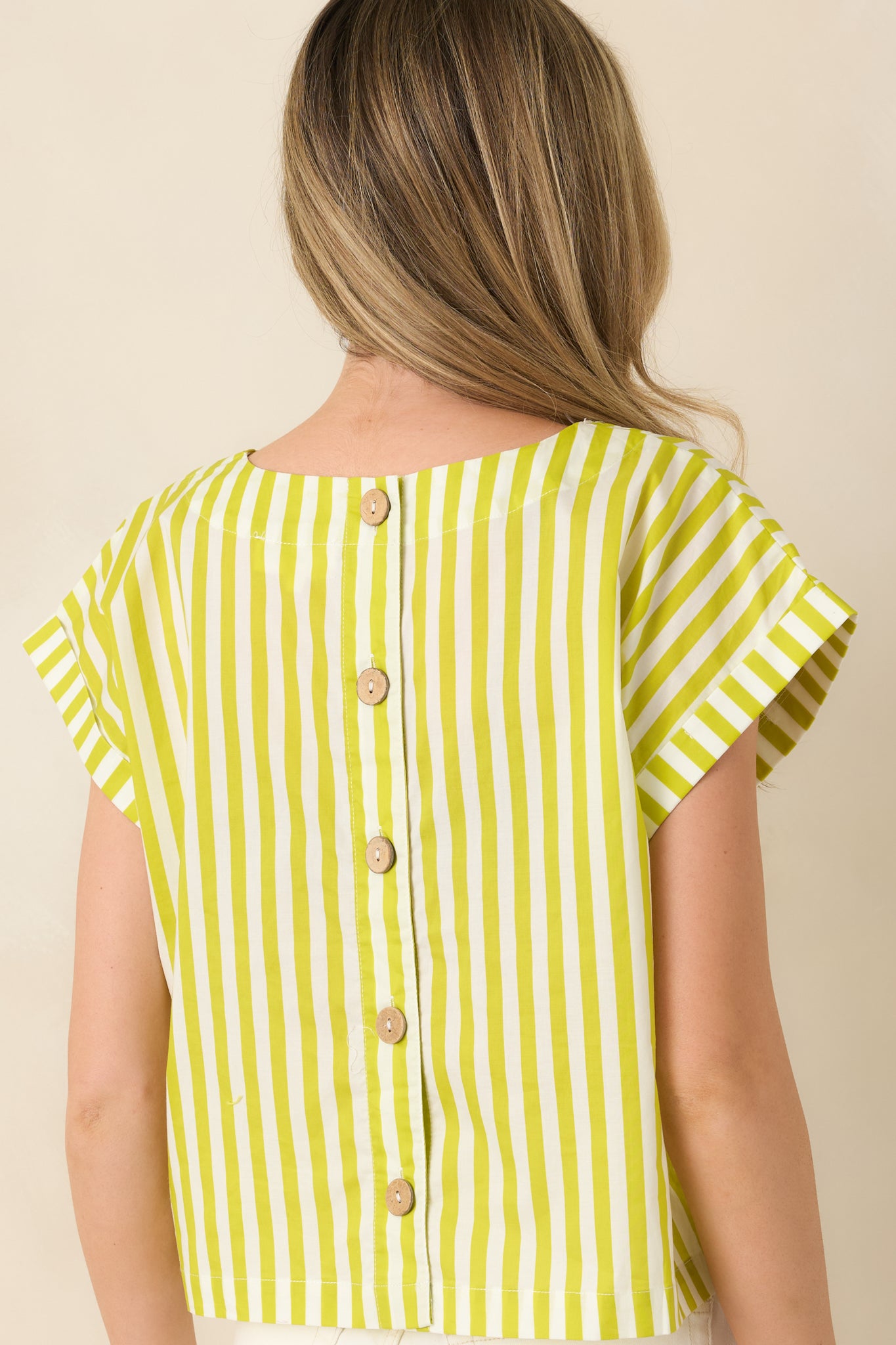 Rear view of the green boxy cotton top displaying the functional button closures and clean stripe continuation across the back.