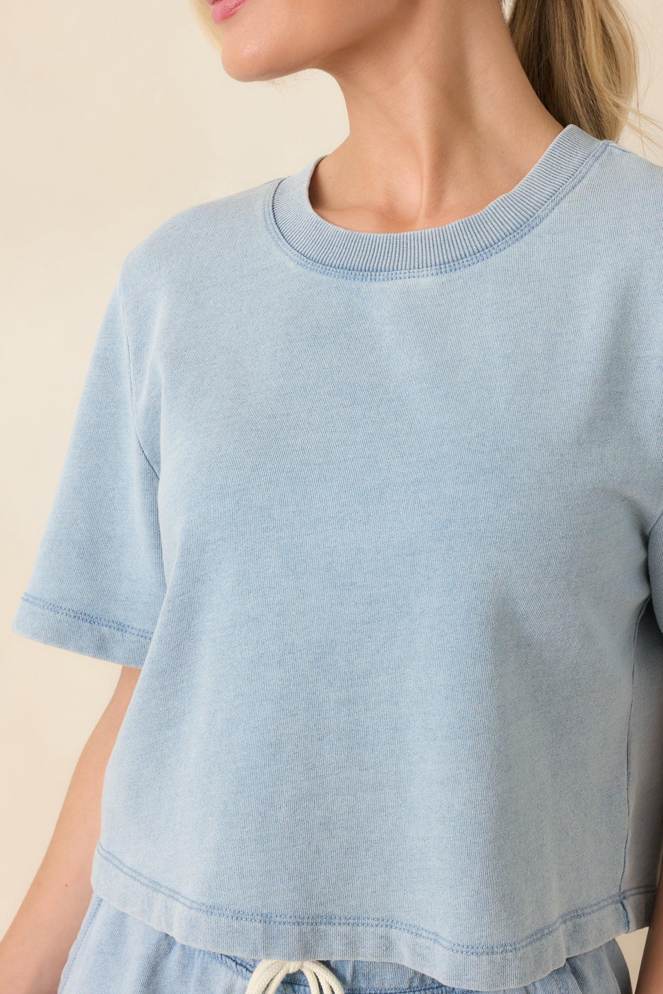 Close-up of denim-style sweatshirt showing fabric texture, crew neckline, and stitching details.