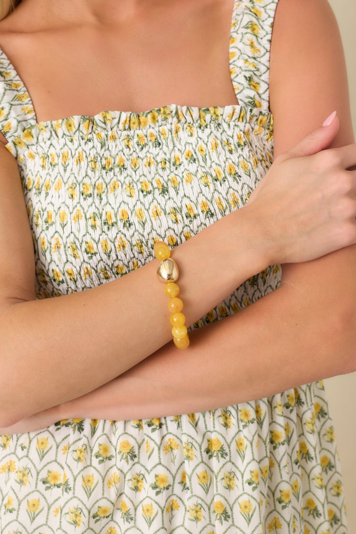 Close-cropped view of the yellow beaded bracelet highlighting the glossy finish of the round beads and central gold-tone accent.