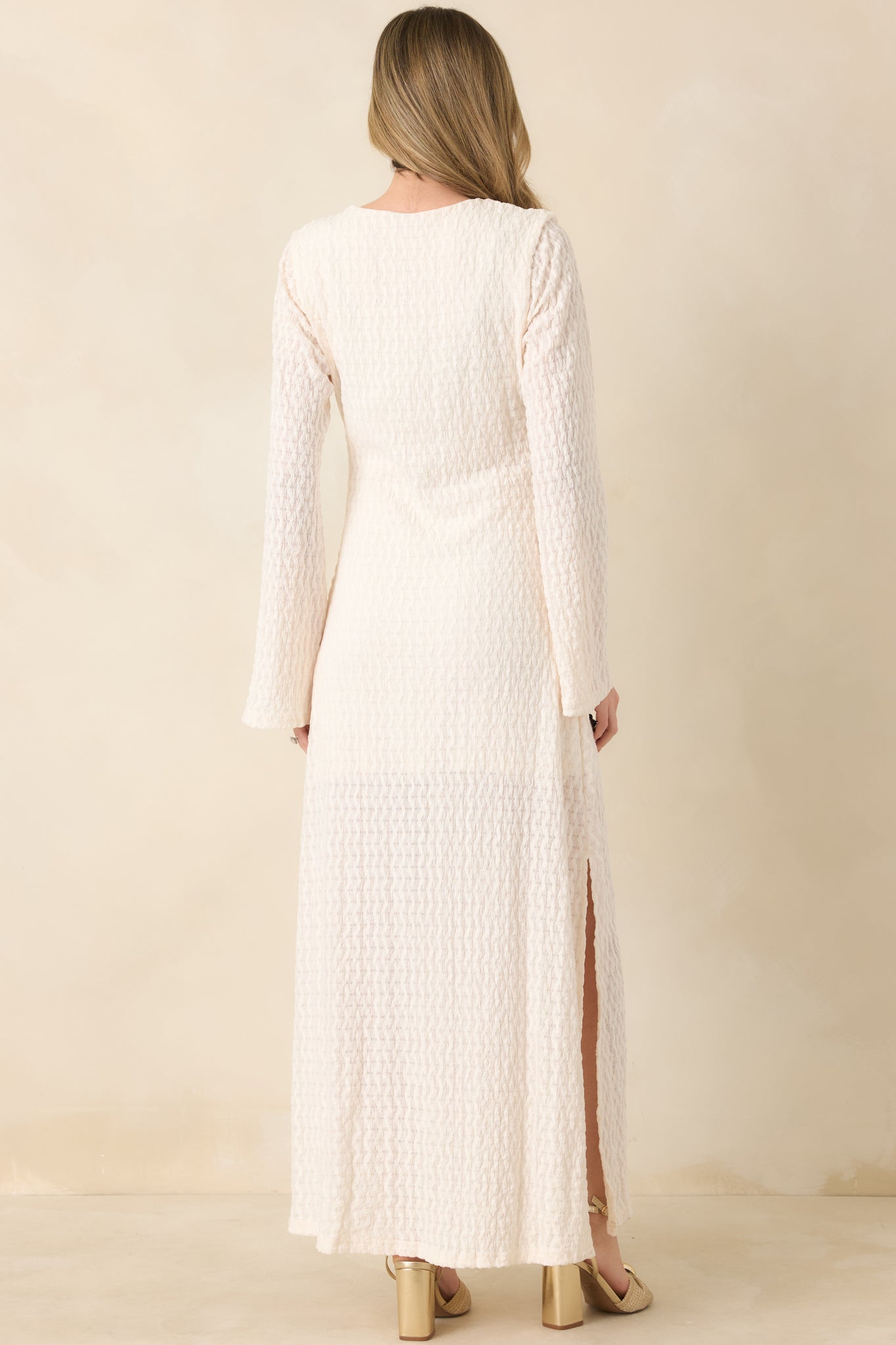Rear view of textured maxi dress with long sleeves and flowing semi-sheer skirt.