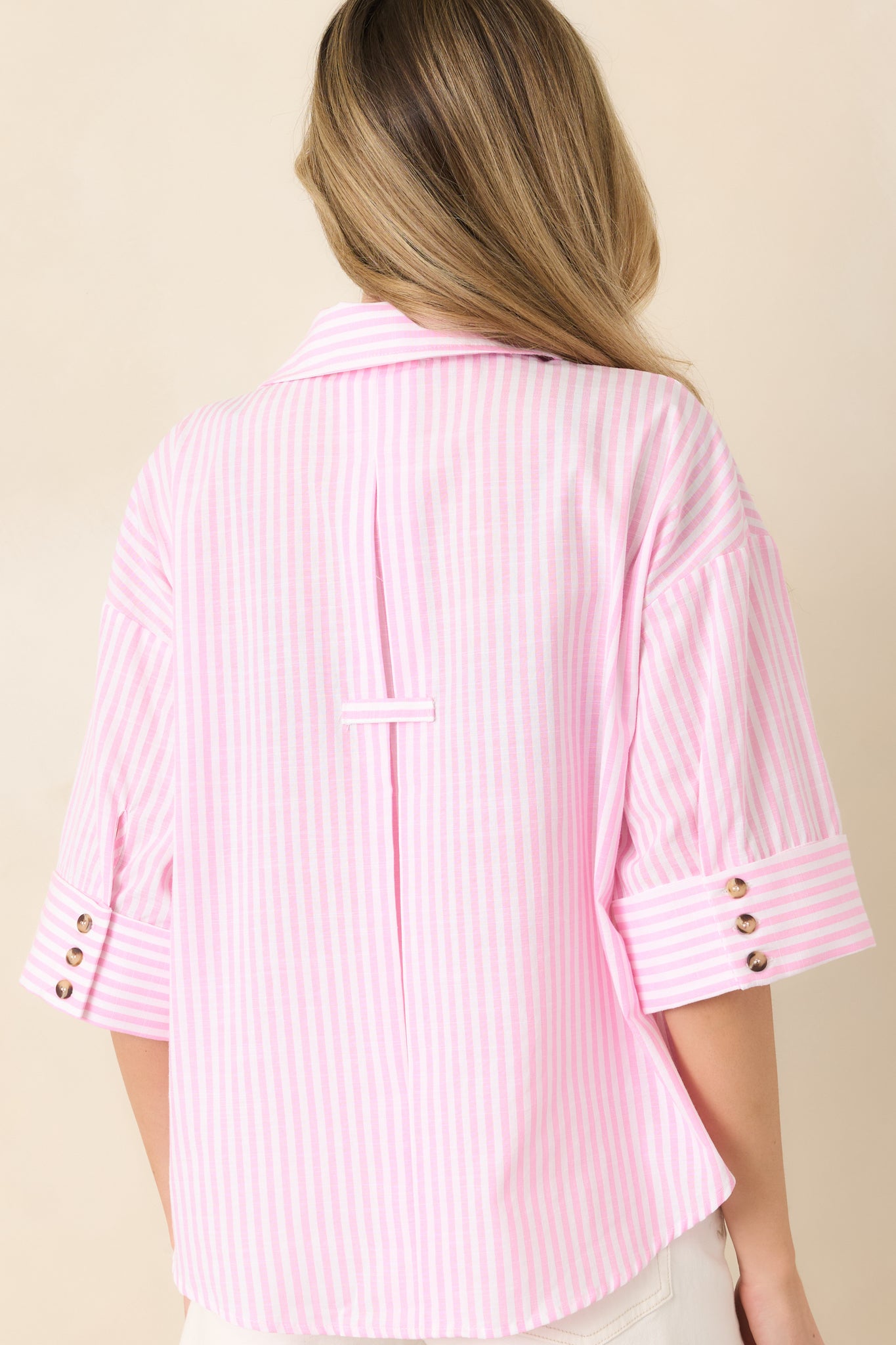 Back view of the pink and white vertical stripe blouse featuring relaxed fit and continuous stripe pattern.