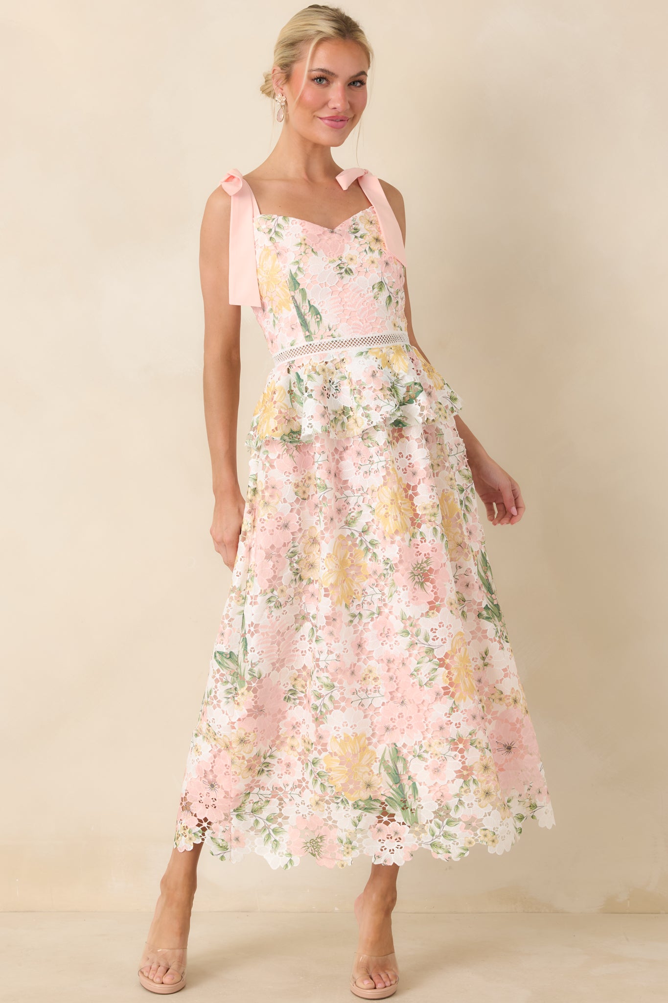 Front view of peach lace floral dress with adjustable tie straps and flowing midi-length skirt.