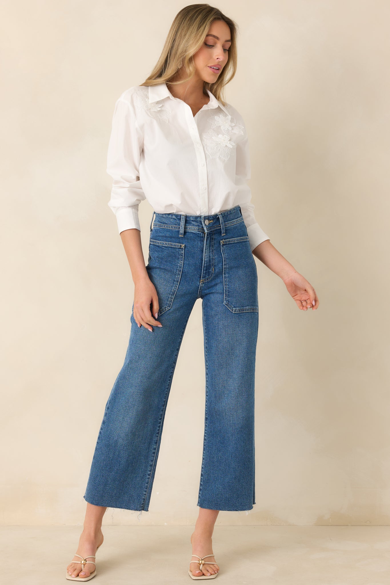 Classic white blouse with long sleeves, collared neckline, and subtle floral appliqué, designed for an easy, flattering fit.