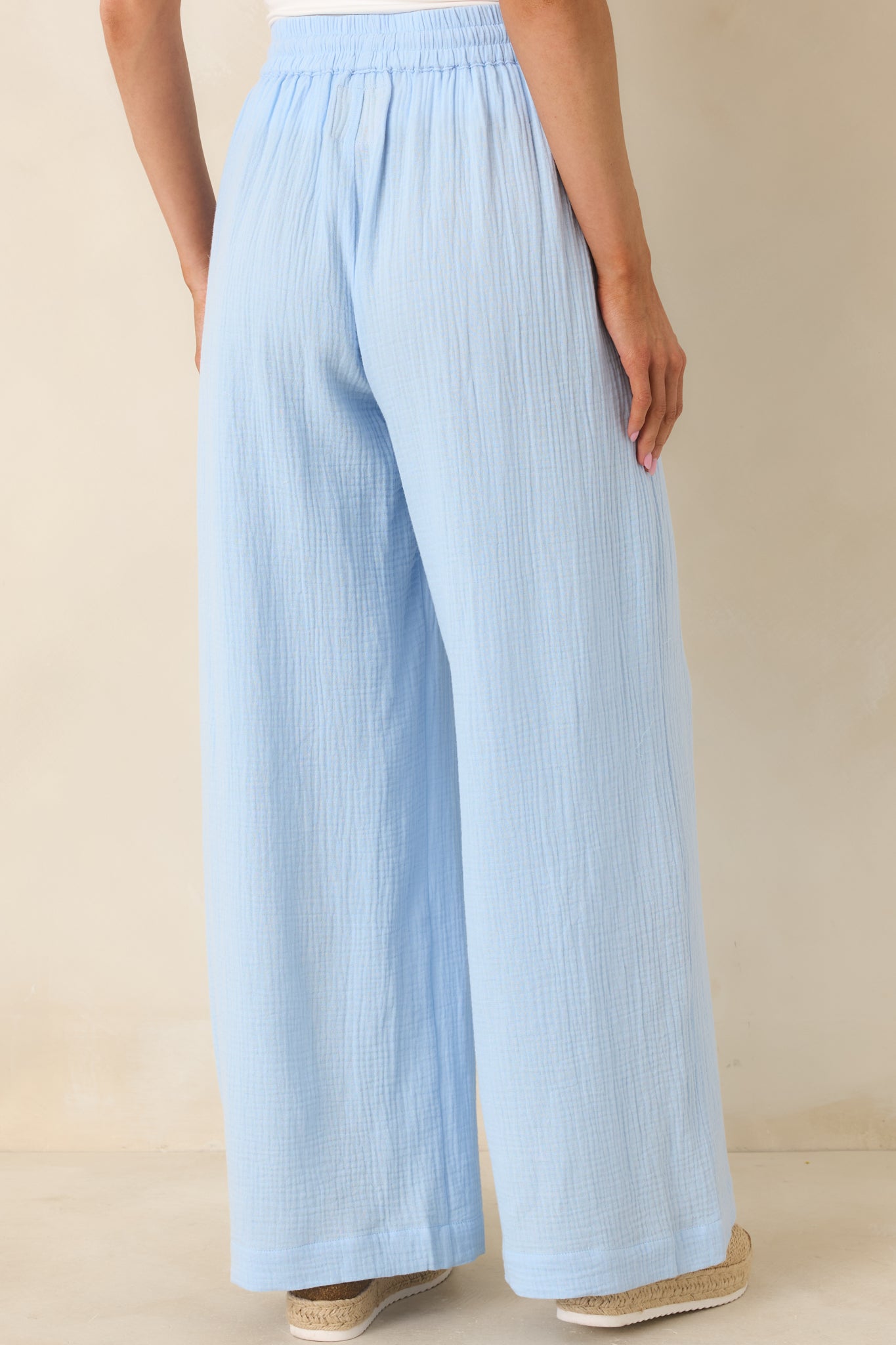 Rear view of blue gauze-style pants featuring elastic waistband, wide-leg fit, and full-length relaxed silhouette.