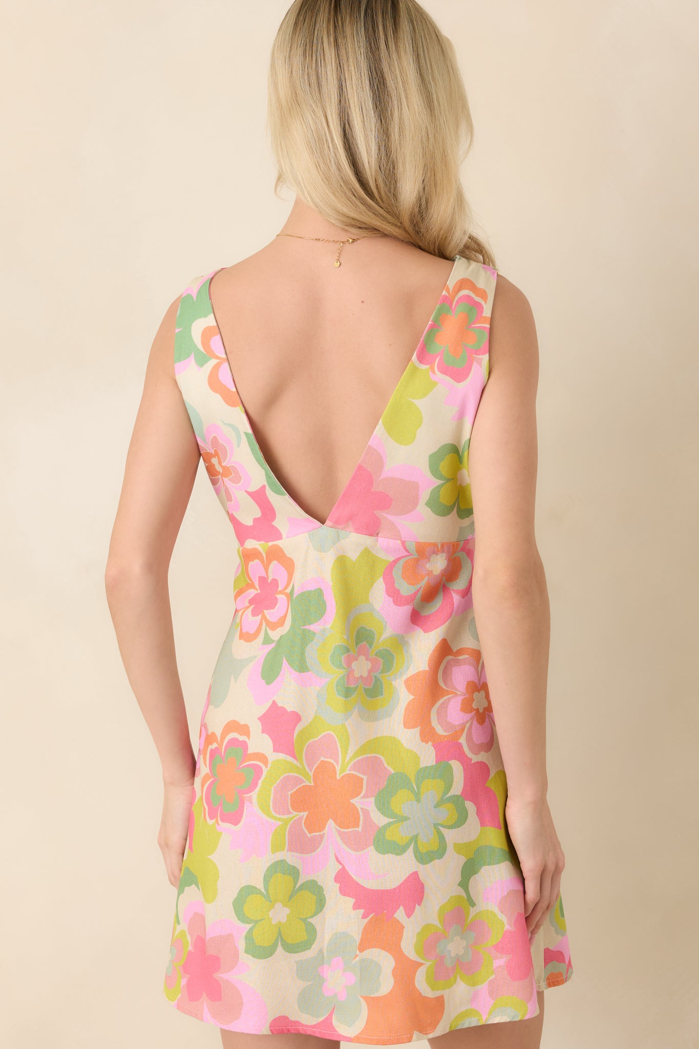 Back view of pink and green multi-floral mini dress featuring a V-neckline, fitted silhouette, and concealed side zipper