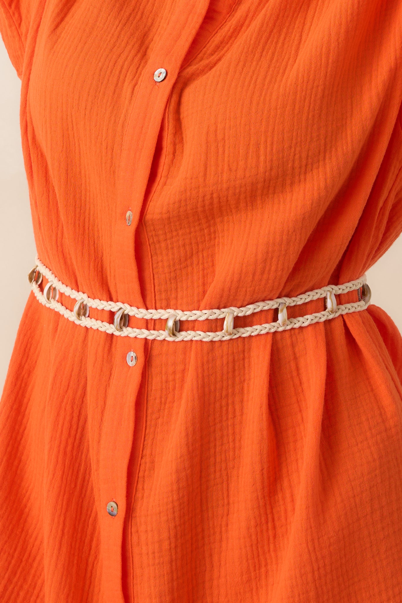 Detailed view of the collared neckline, button-front closure, and woven belt on textured cotton.