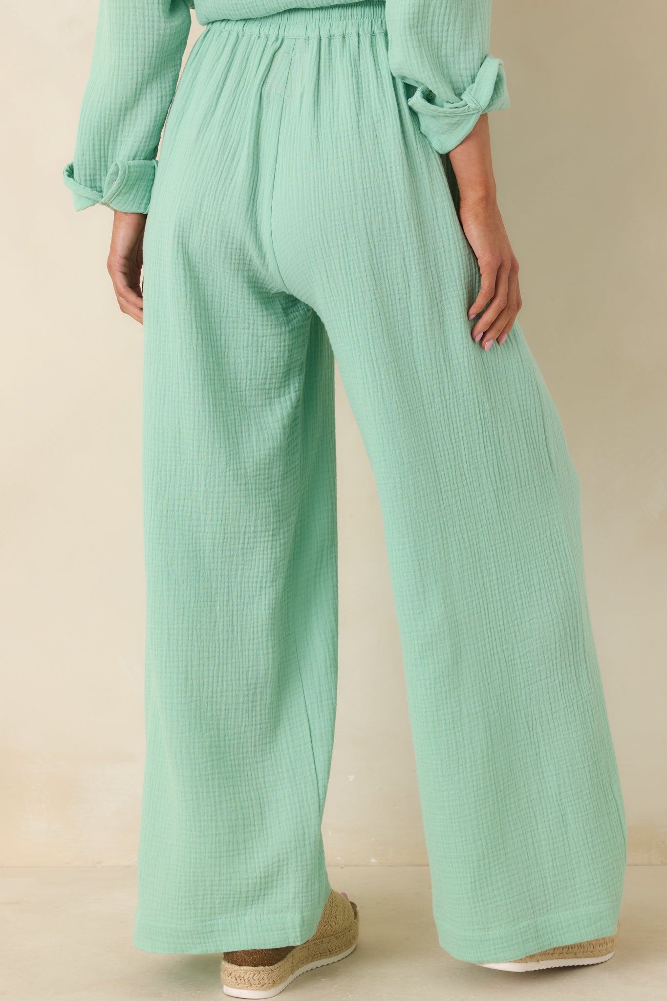 Rear view of seafoam green wide-leg pants featuring elastic waistband and relaxed full-length silhouette.