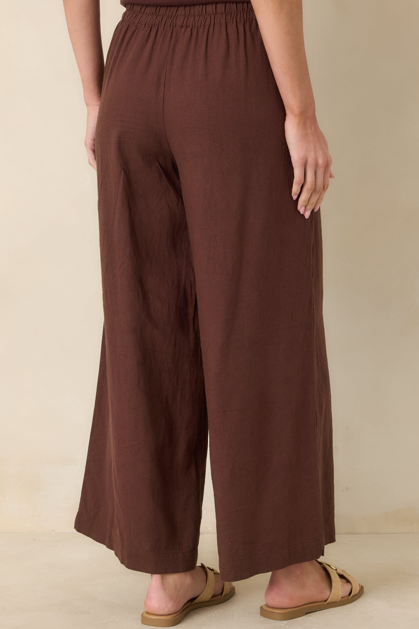 Back view of linen pants with relaxed wide-leg silhouette, functional side pockets, and smooth, flowing fit.
