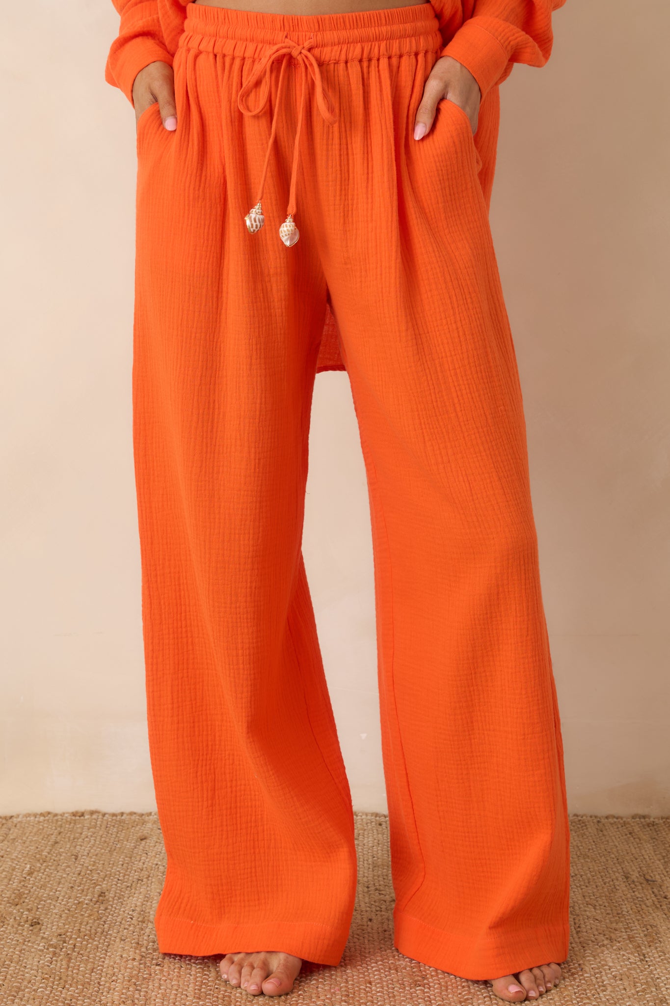 Cropped view of orange textured cotton pants highlighting the elastic waistband and adjustable drawstring detail.