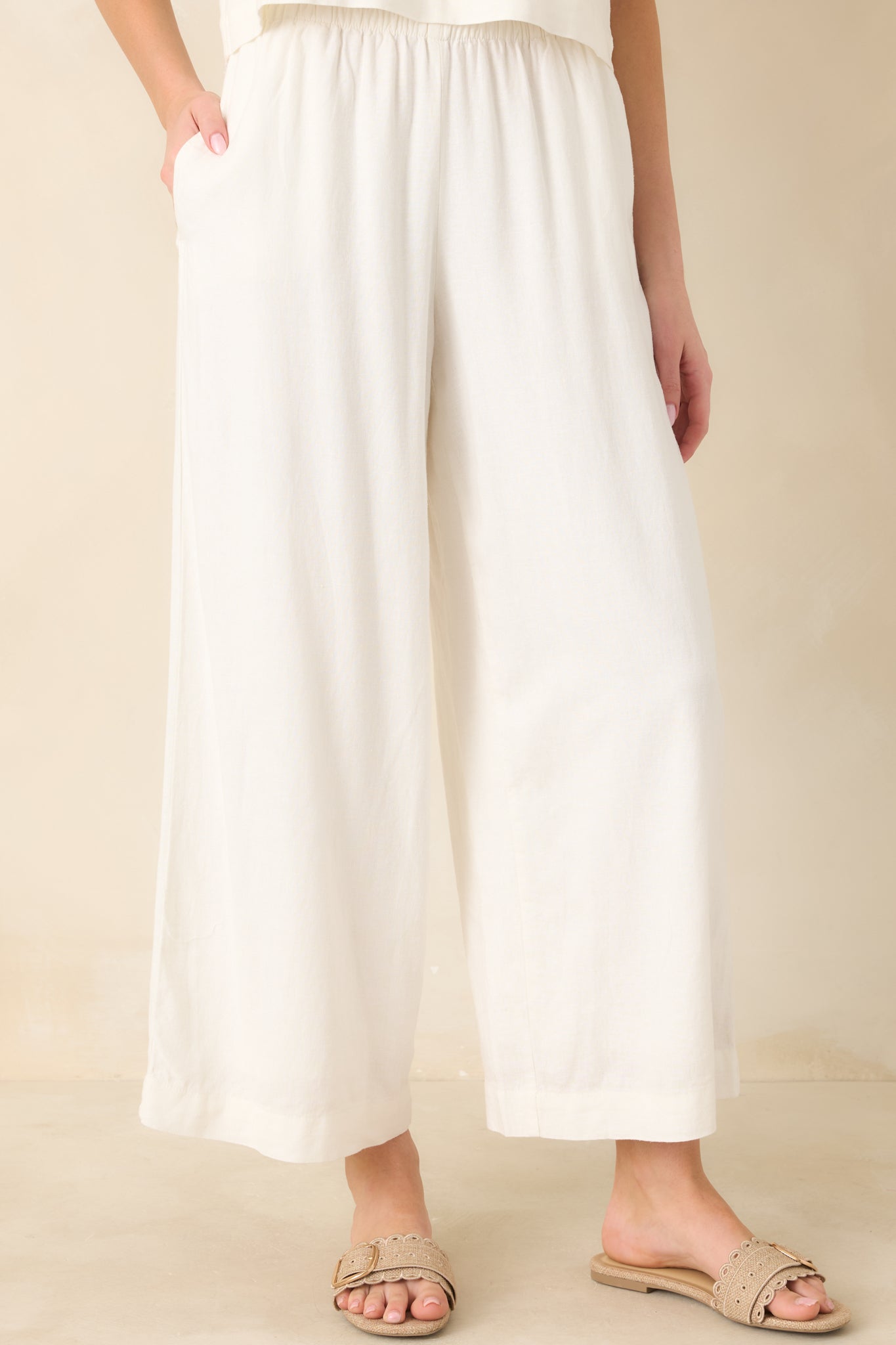 Detail-focused view of the white linen fabric emphasizing the pull-on waistband and easy, flowing leg silhouette.