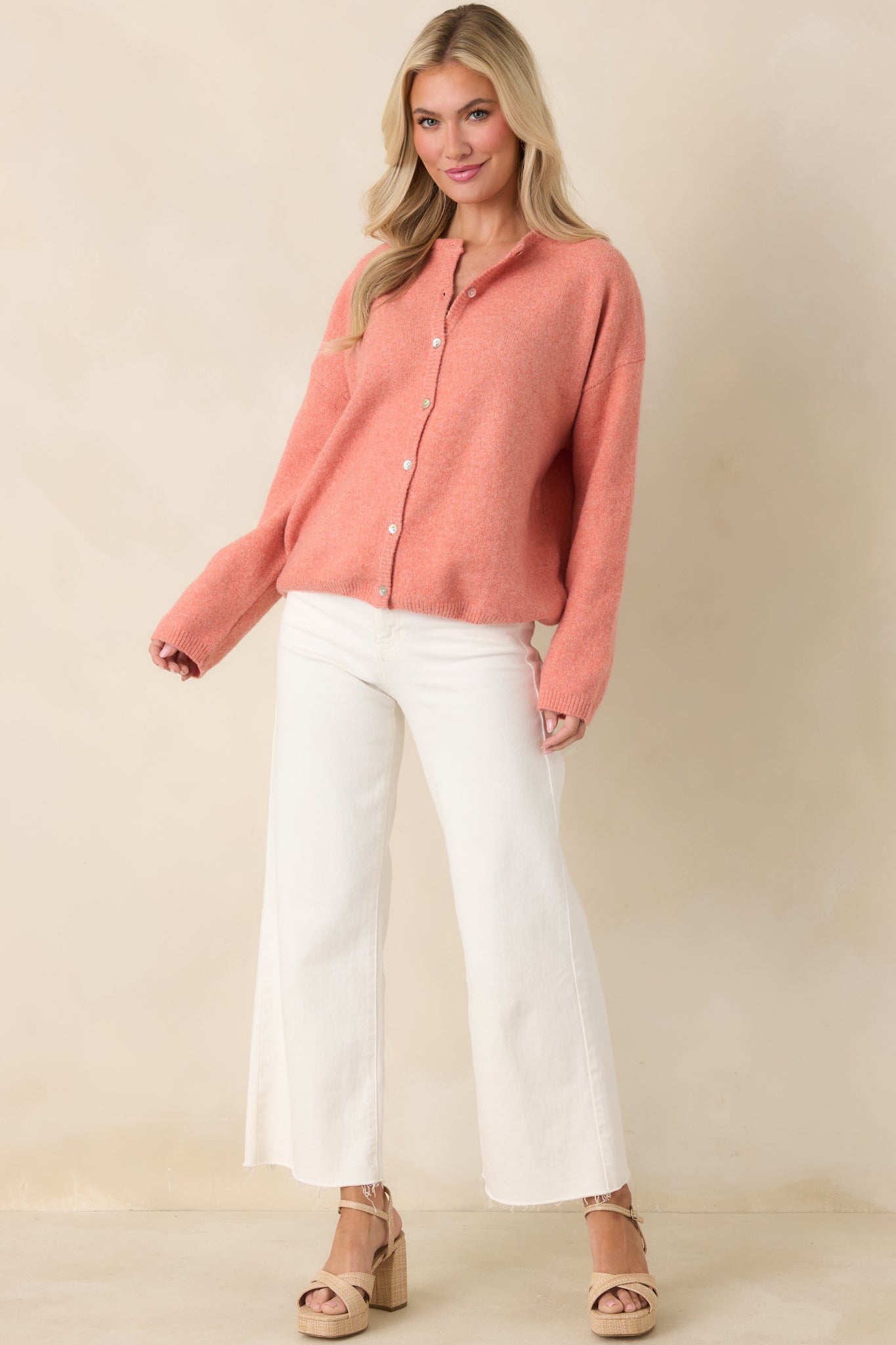 Orange knit cardigan with a button-front closure, round neckline, and long sleeves in a relaxed, easygoing silhouette.