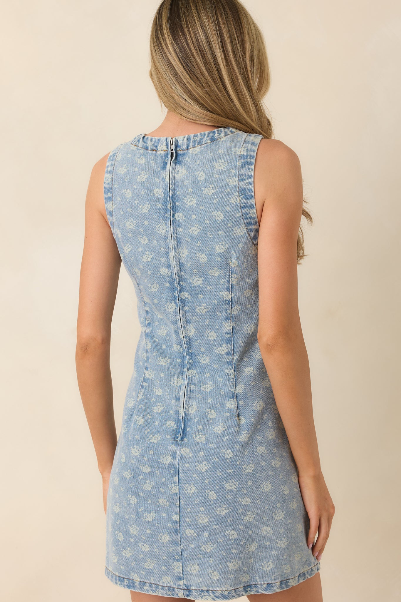 Rear view of the light wash denim mini dress showing the hidden zipper closure and gently flared hem.