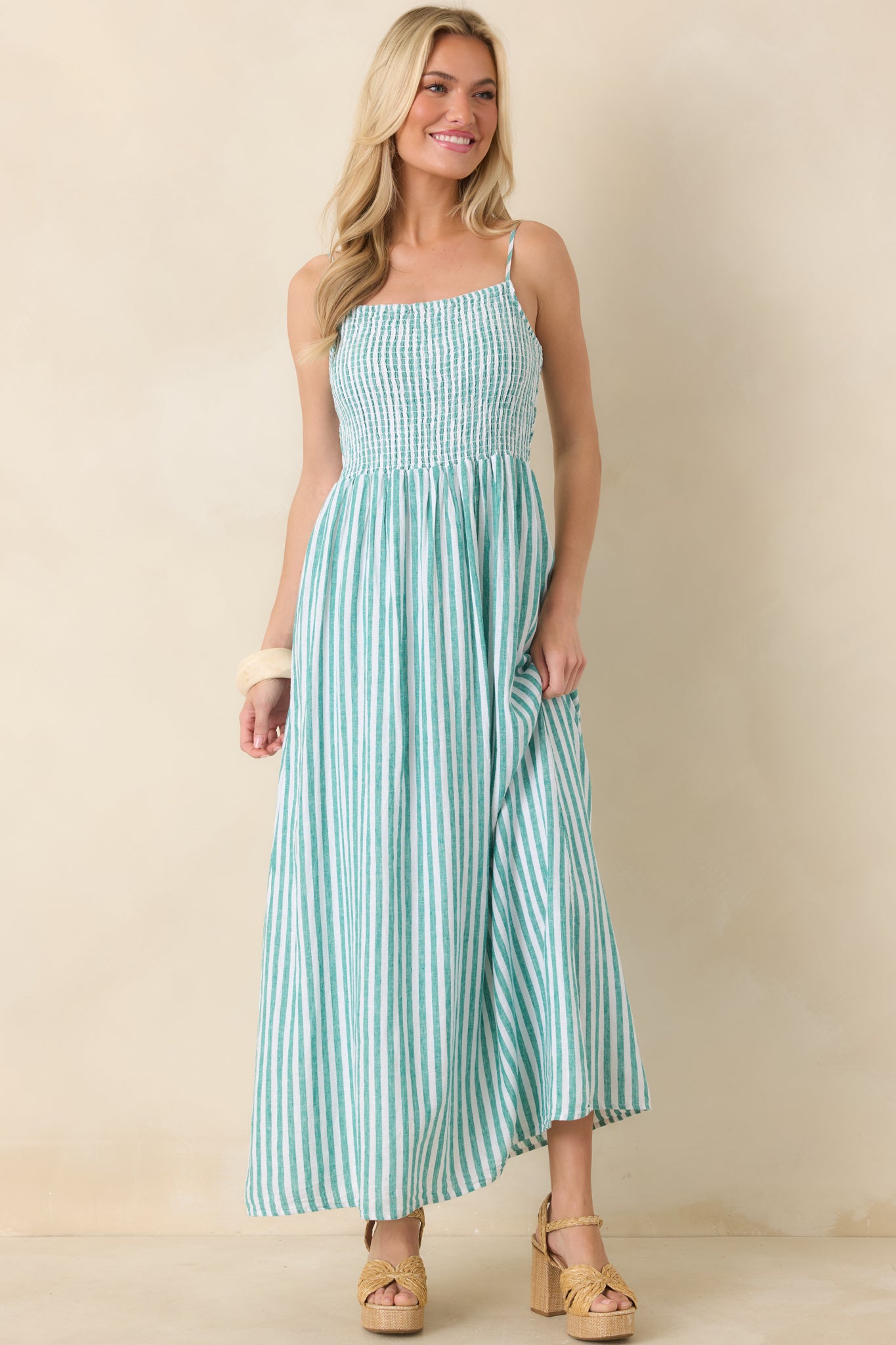 Front view of a green striped linen maxi dress with a smocked bodice and flowing skirt.