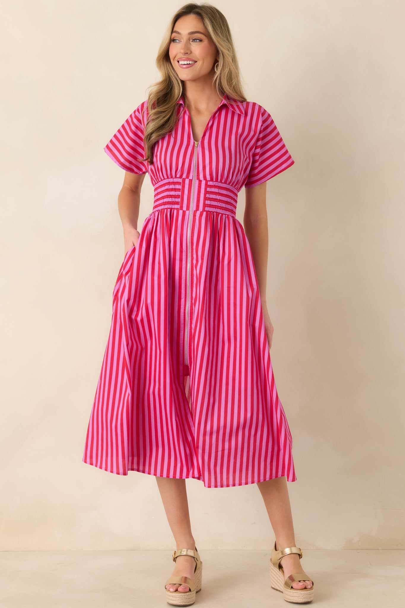 Striped cotton midi dress in pink and red featuring a structured collar, front zipper detail, functional pockets, and a softly flared A-line silhouette.