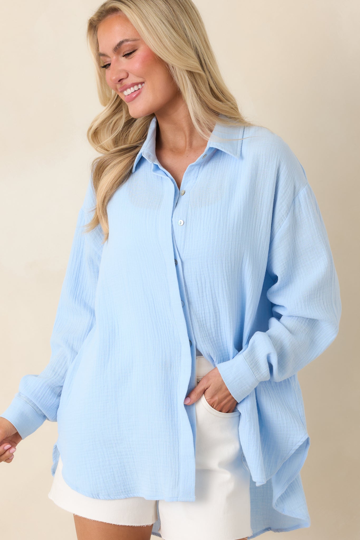 Button cuff detail on long sleeve of lightweight blue cotton button-up.