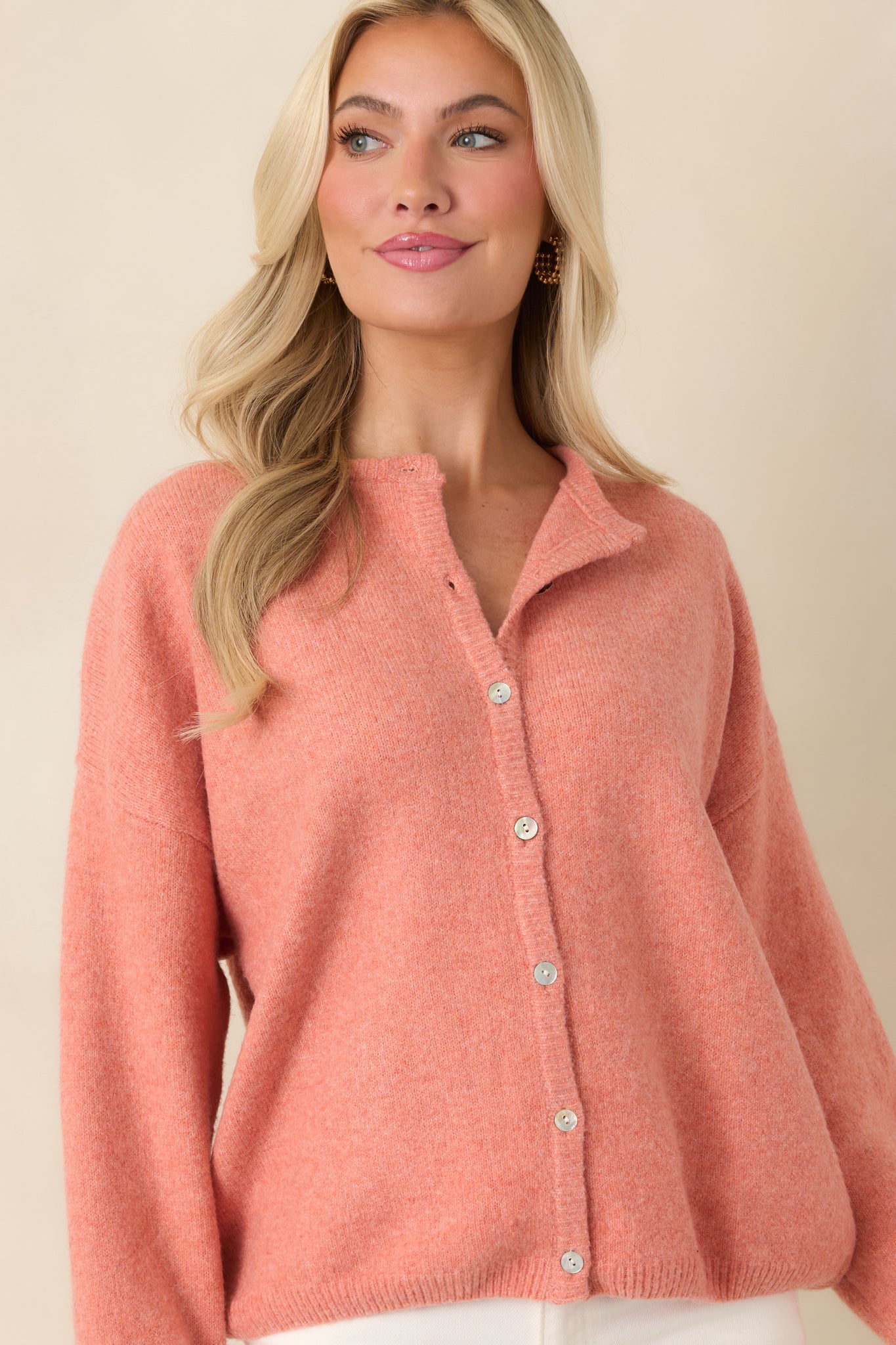 Focus on the long sleeves and relaxed fit, showing the drape and vibrant orange color of the knit.