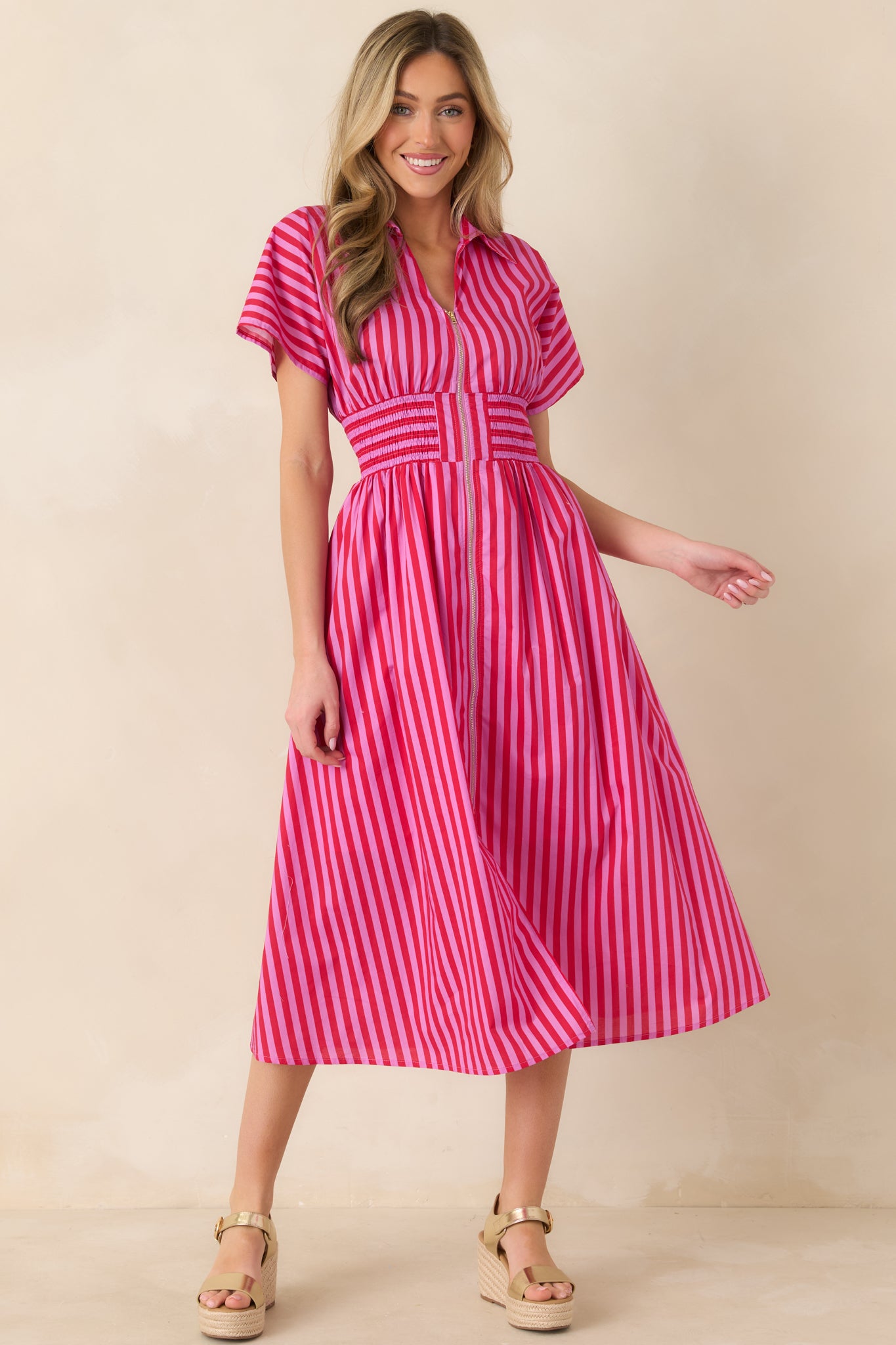 Pink and red striped midi dress with structured collar, zip-front closure, short sleeves, wide smocked waistband, and a flowy A-line skirt in lightweight cotton.