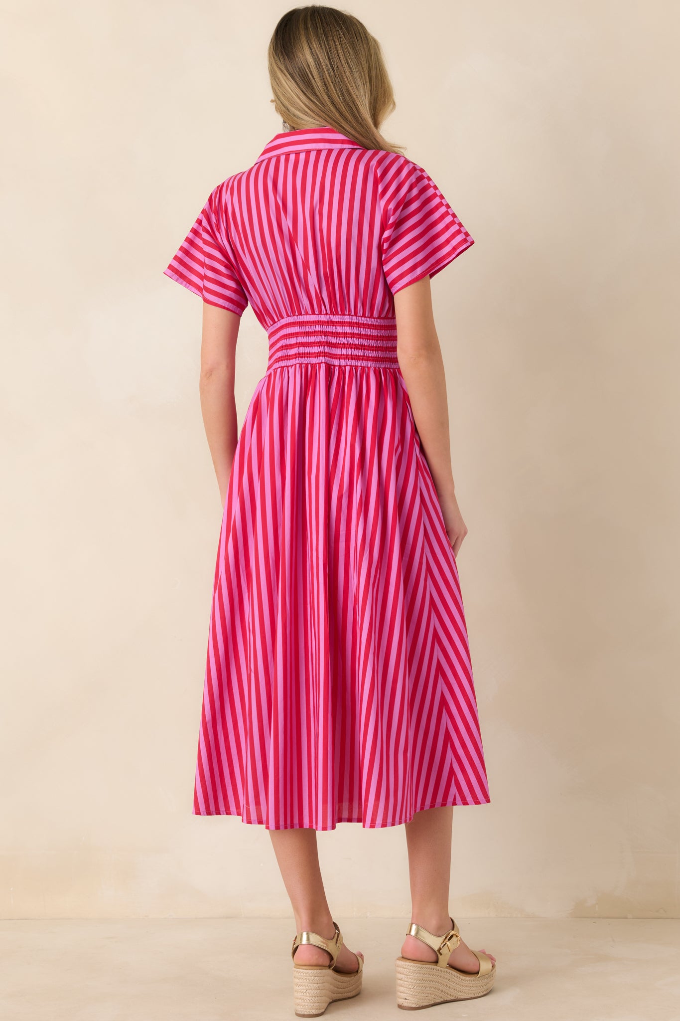 Rear view of pink and red striped midi dress featuring short sleeves, a defined smocked waistband, and a full A-line skirt in lightweight woven cotton.
