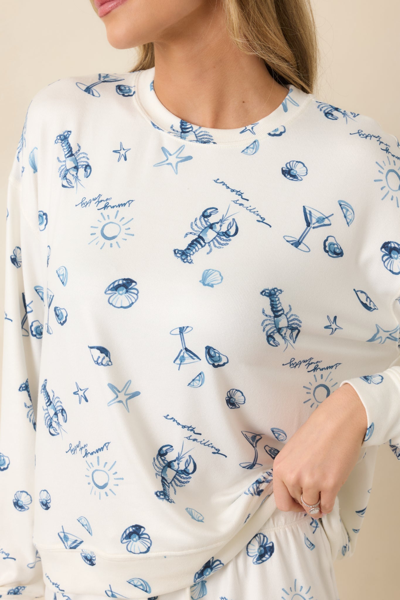 Close-up of blue seaside graphics including lobsters, shells, and starfish on soft ivory fabric.