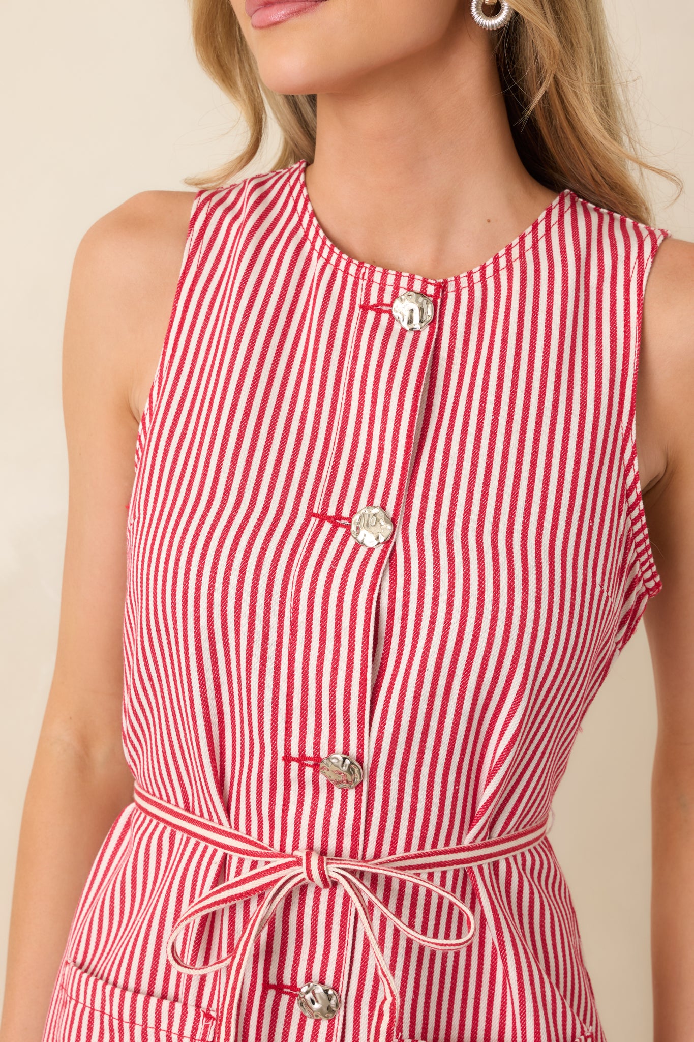 Close view of the red and white striped fabric featuring button-front hardware and stitching along the patch pocket.