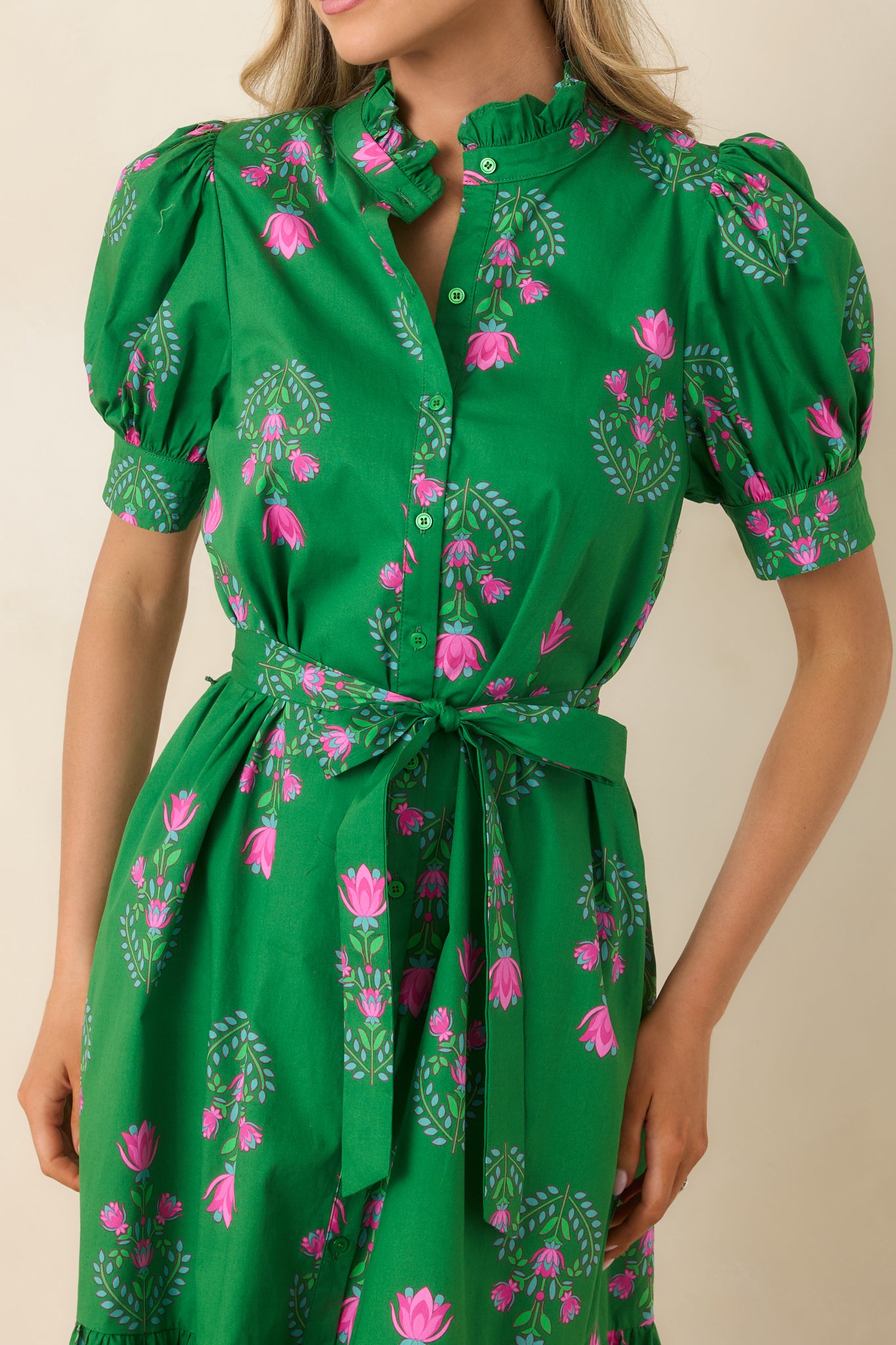 Close-up of the floral pattern, puff sleeve stitching, ruffle collar, and button-front detail of the green midi dress.