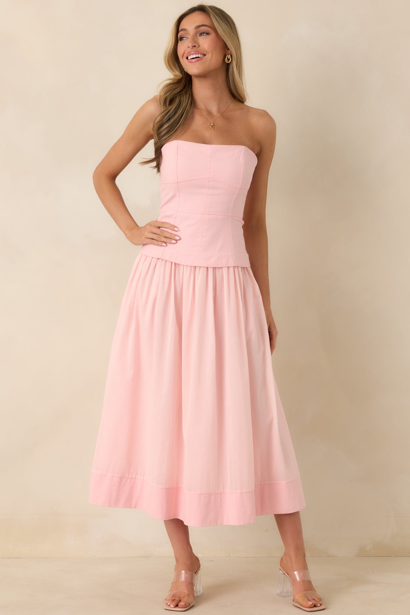 Pink dress with structured paneled bodice, spaghetti straps, and a draped gathered skirt offering a fluid silhouette and pocket details.