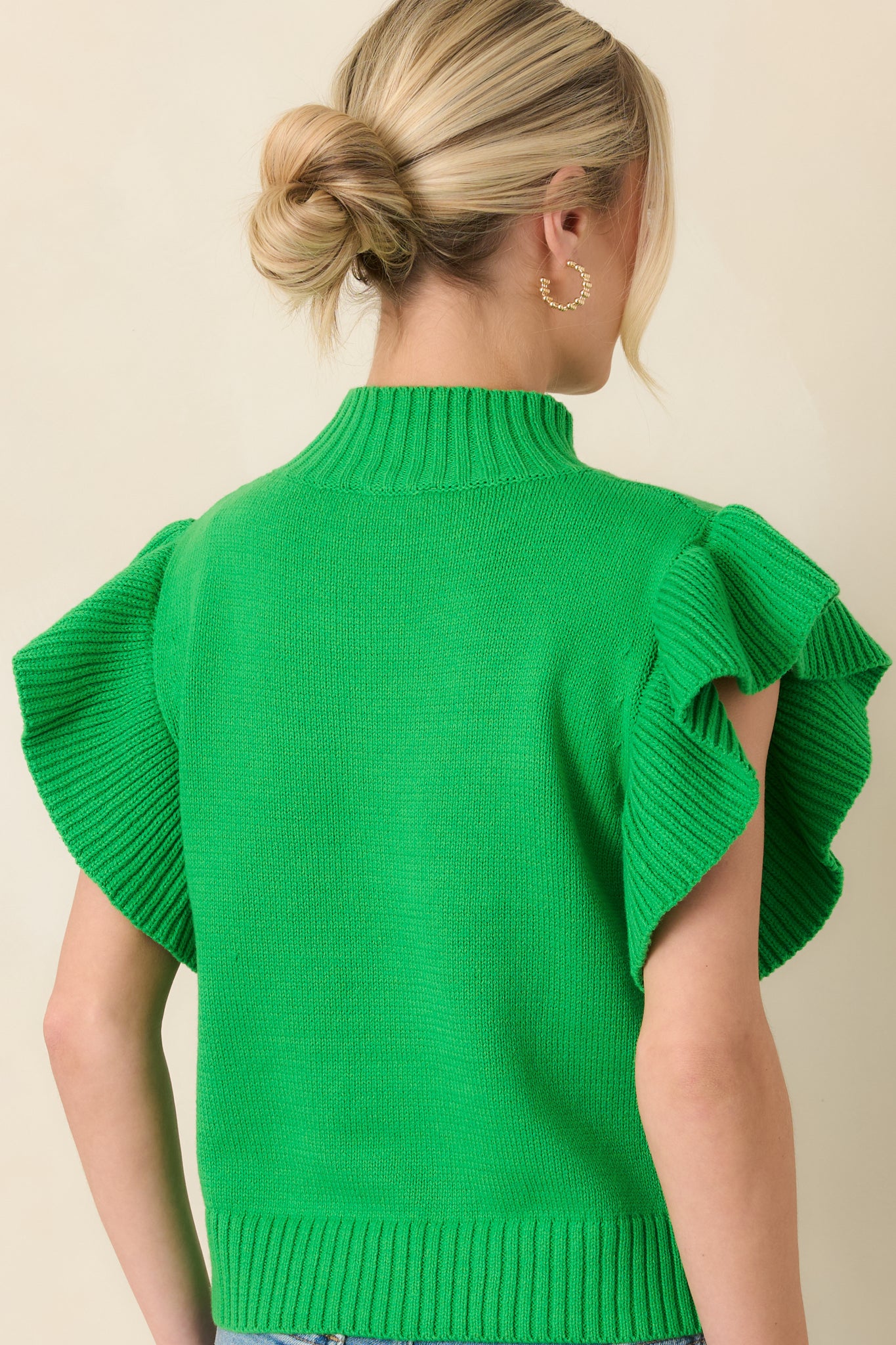 Rear view of the green knit top displaying the smooth knit body and ribbed hem finish.