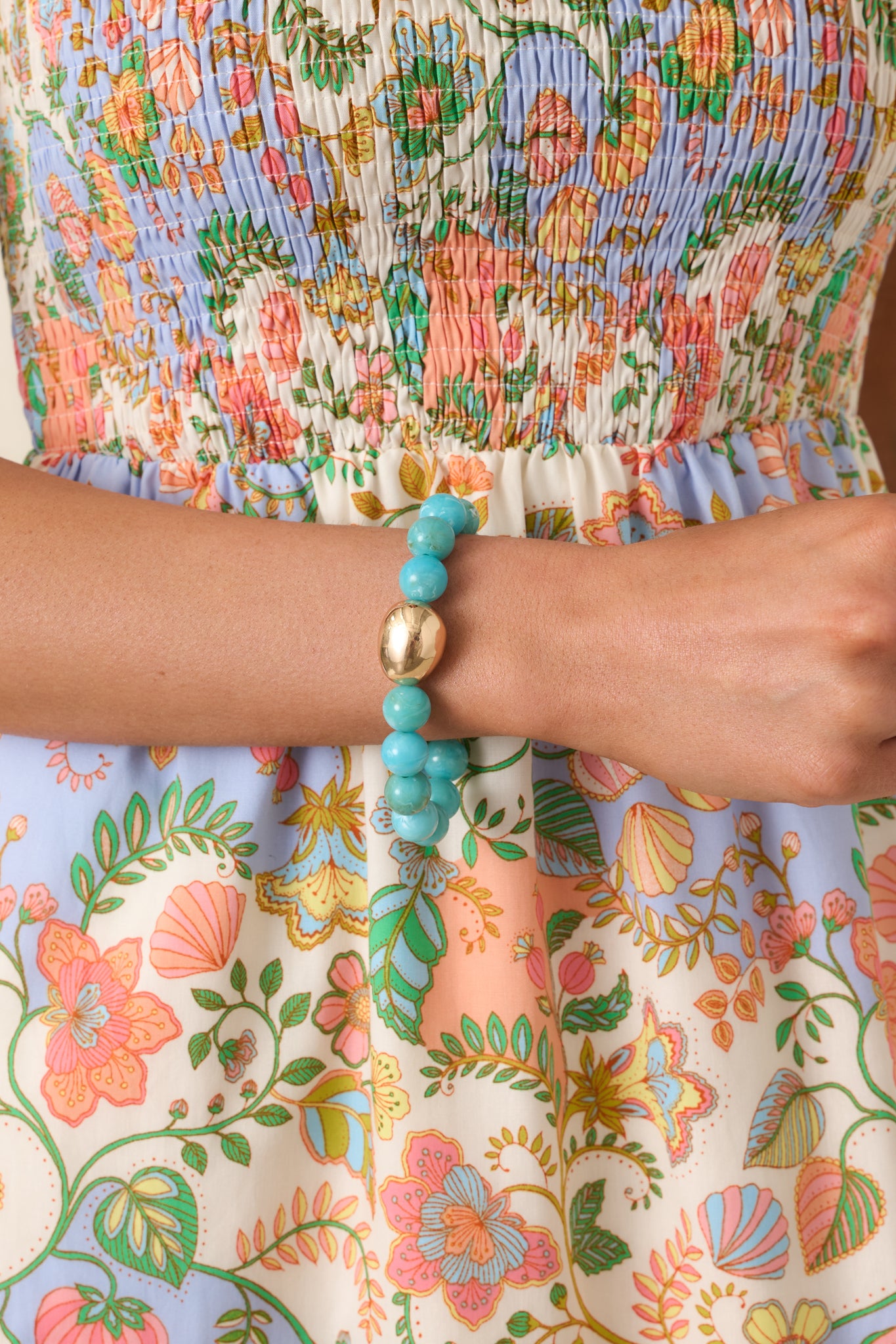 Close-up of the polished gold-tone accent bead and surrounding turquoise beads on the elastic bracelet.