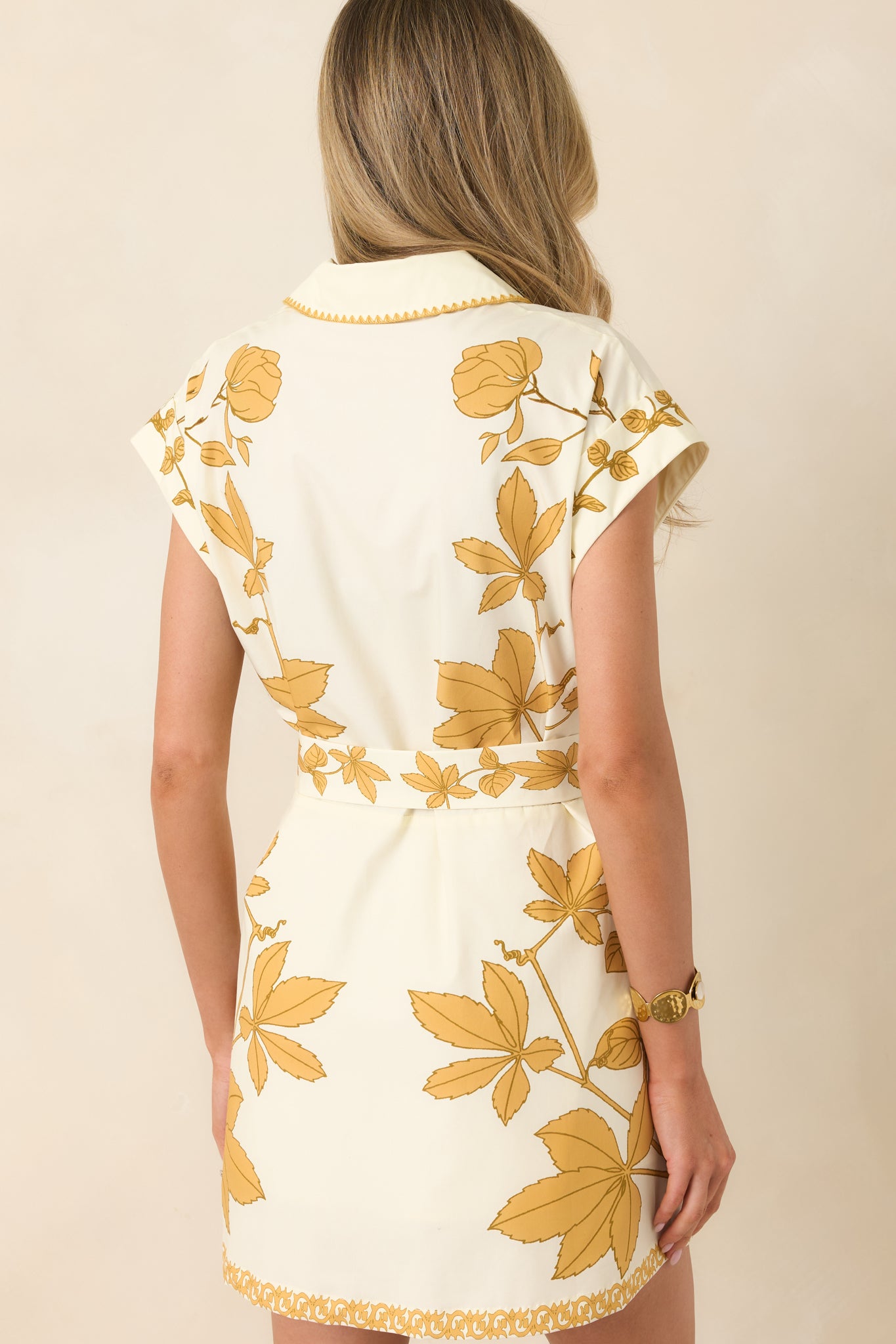 Back view of mini dress with cap sleeves, soft floral print, and gently tailored silhouette.