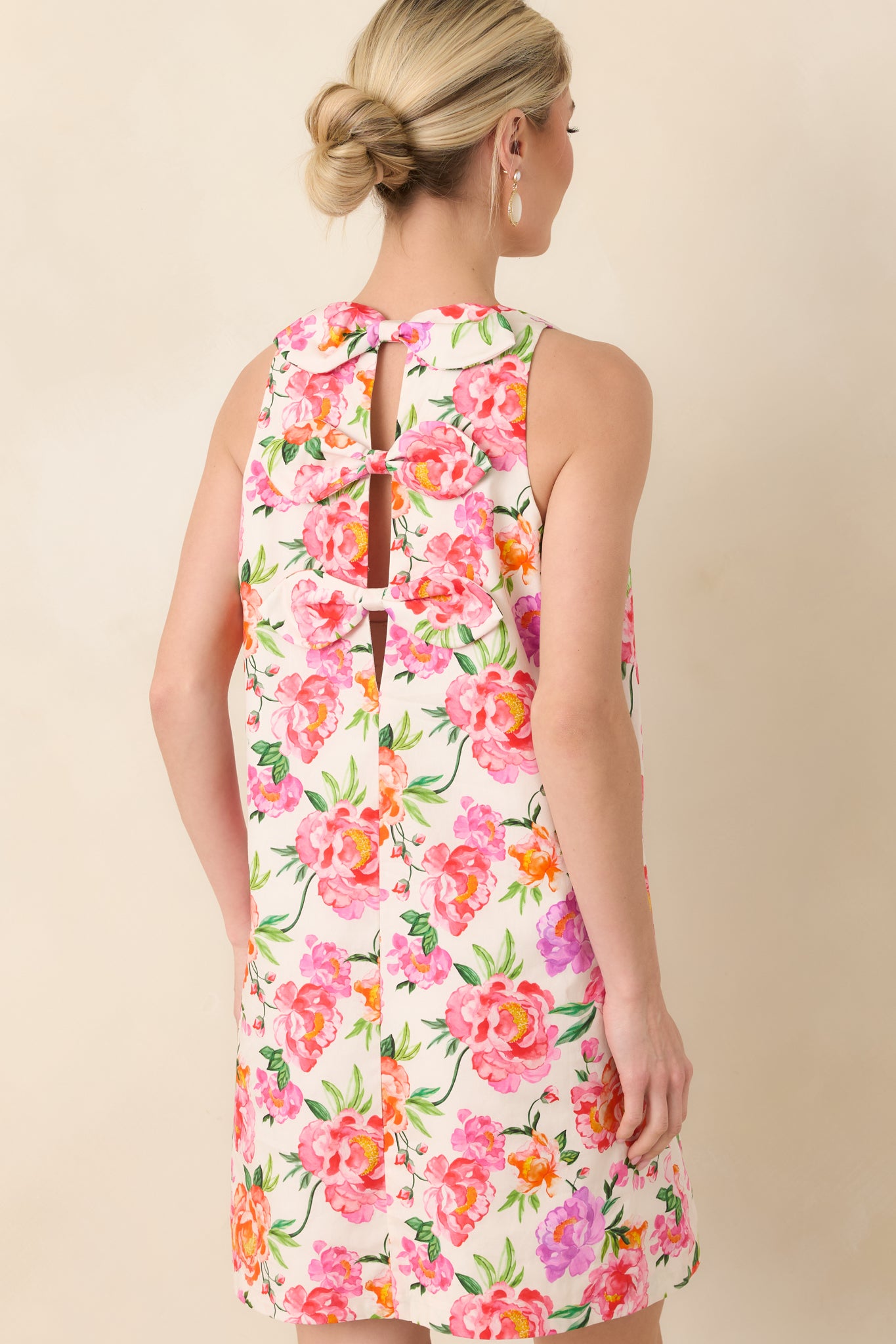 Back view of the pink multi floral cotton mini dress featuring layered bow accents cascading down the back.