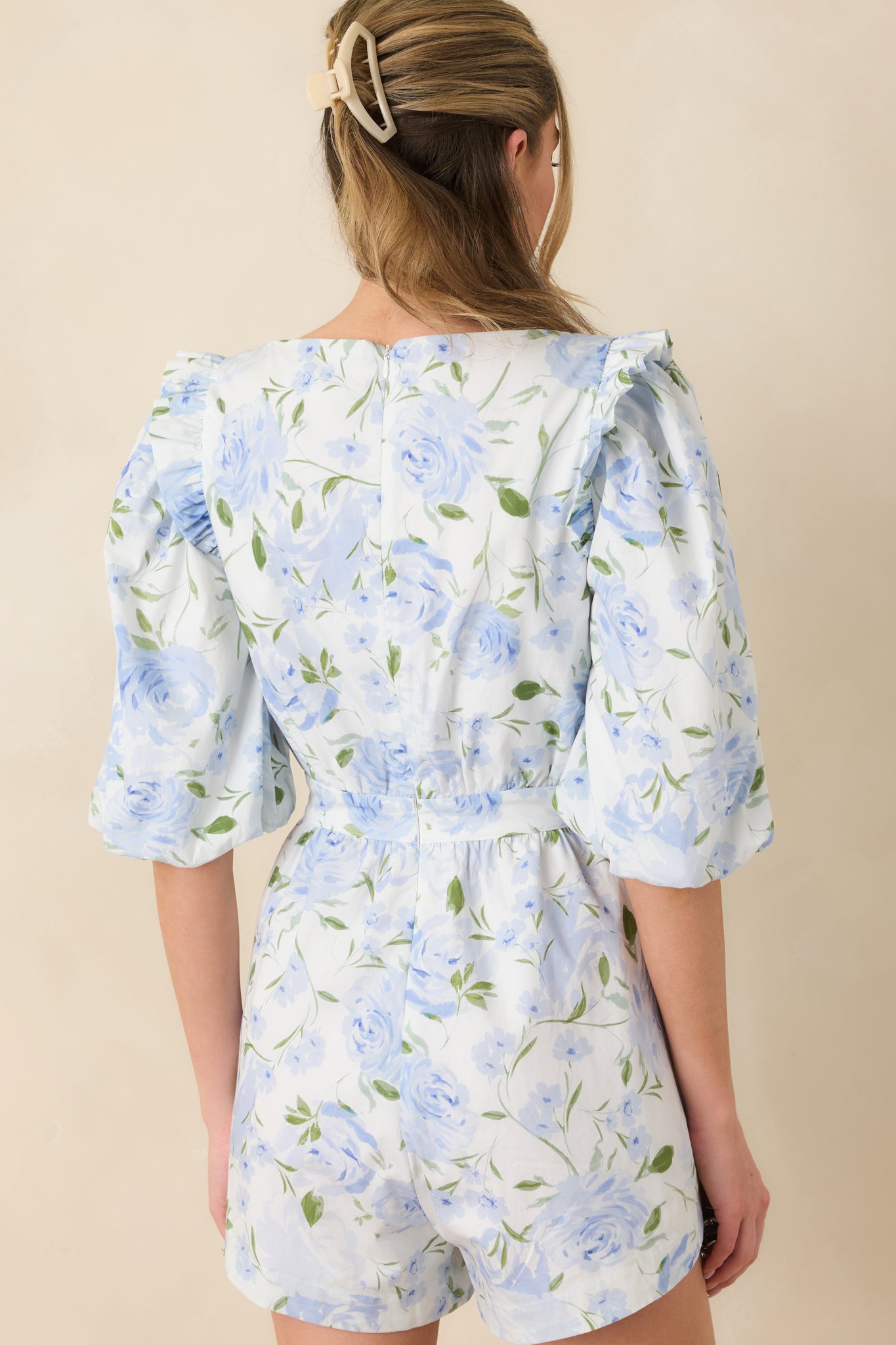 Back view of the blue floral romper showing the concealed back zipper and clean waistband finish.