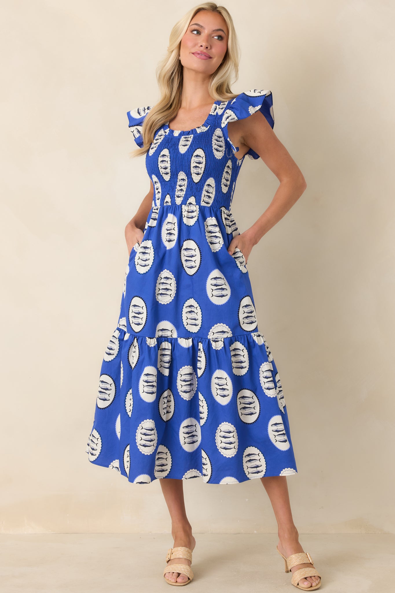Cotton midi dress in bold blue with charming fish pattern, featuring elastic smocking at the bodice and a flowy tiered skirt that creates graceful movement.