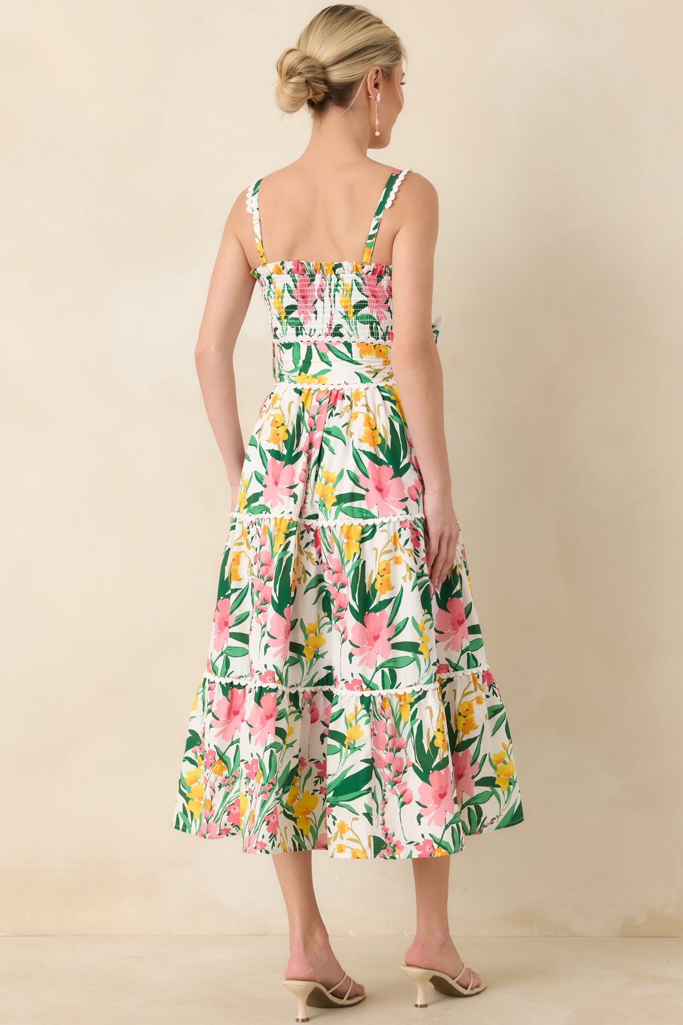 Rear view of midi dress showing smocked bodice, tie belt with bow, and flowing tiered skirt in floral print.