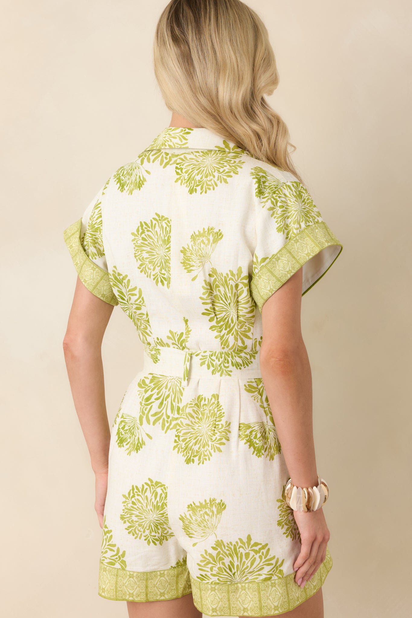 Back view of romper showing relaxed fit, floral print, cap sleeves, and self-tie belt at the waist.
