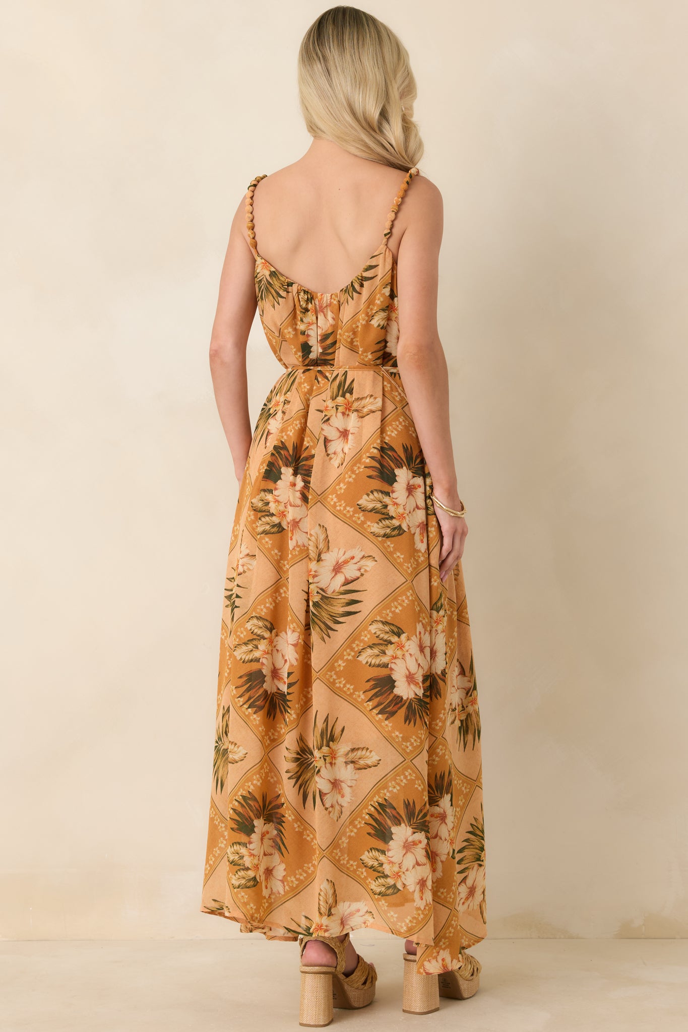 Back view of a peach multi tropical print maxi dress with flowing skirt, beaded straps, and adjustable self-tie waist.