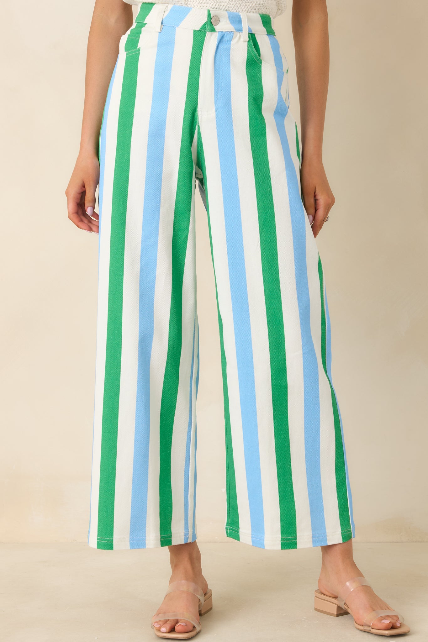 High-rise waistband of green, blue, and white striped pants highlighting belt loops and zipper button closure.