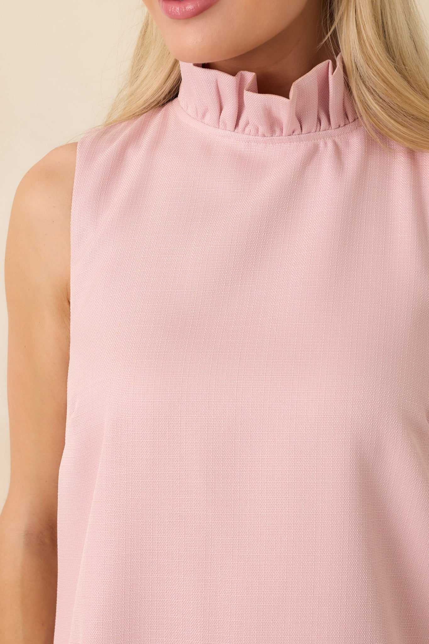 Close-up view of the pink mini dress highlighting the smooth fabric, mock neckline, and refined stitching.