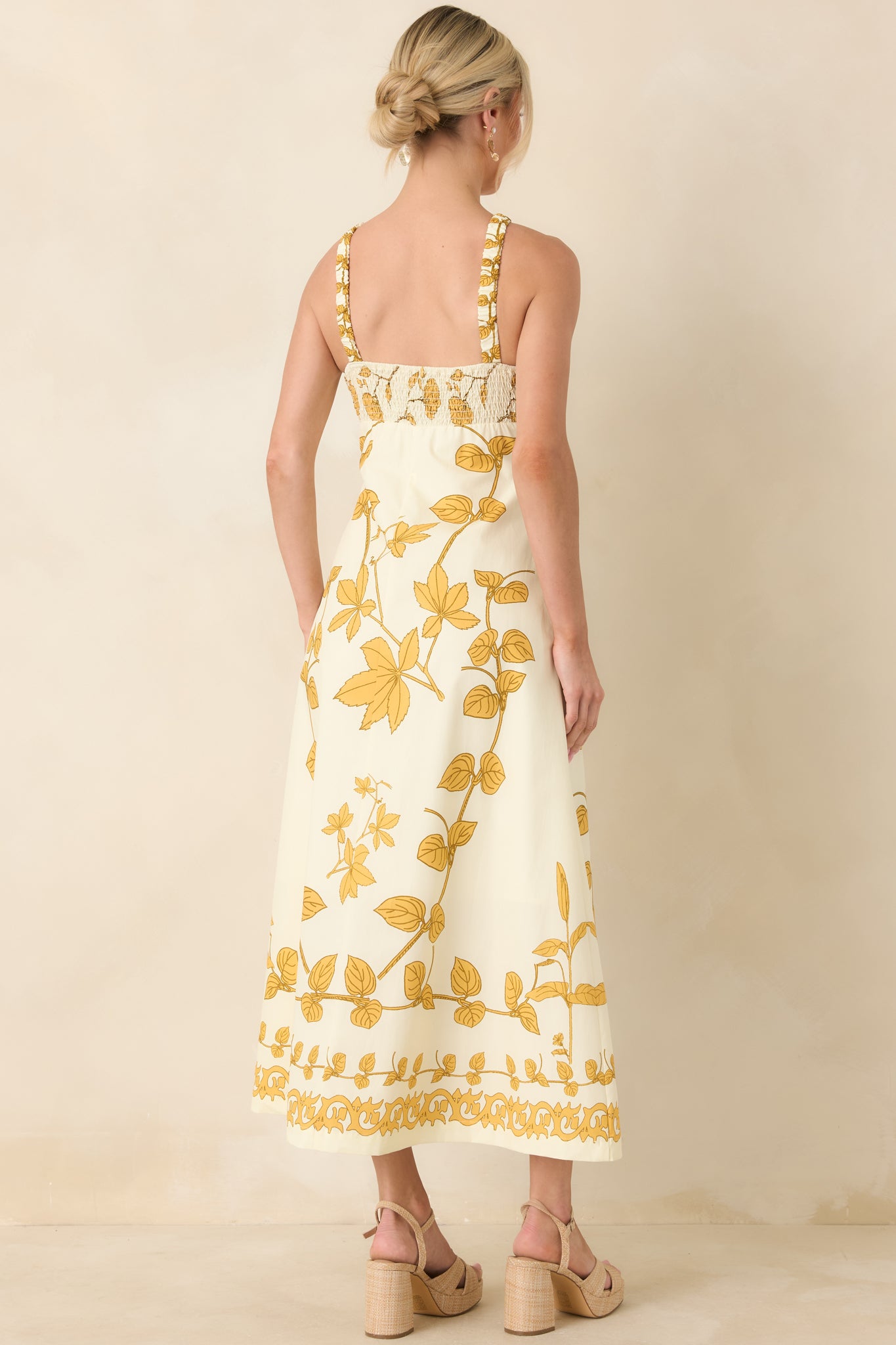 Back view of halter neck maxi dress showing crossed straps, smooth bodice, flowing full-length skirt, and floral print.