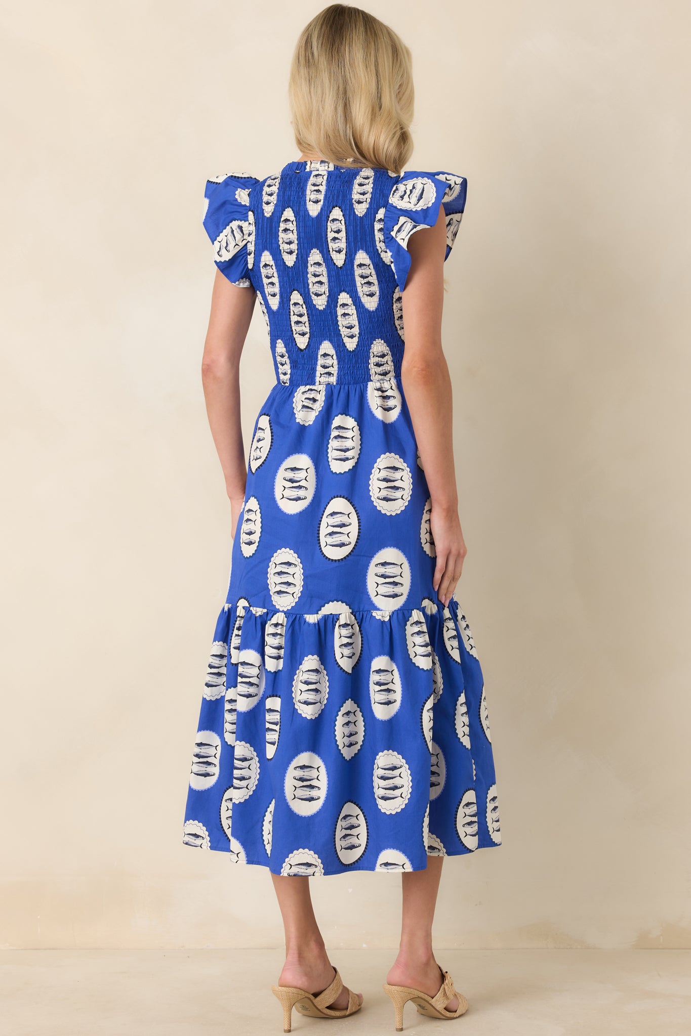 Rear view of the royal blue fish print dress displaying the fully smocked bodice and the softly gathered tiers flowing into a breezy skirt.
