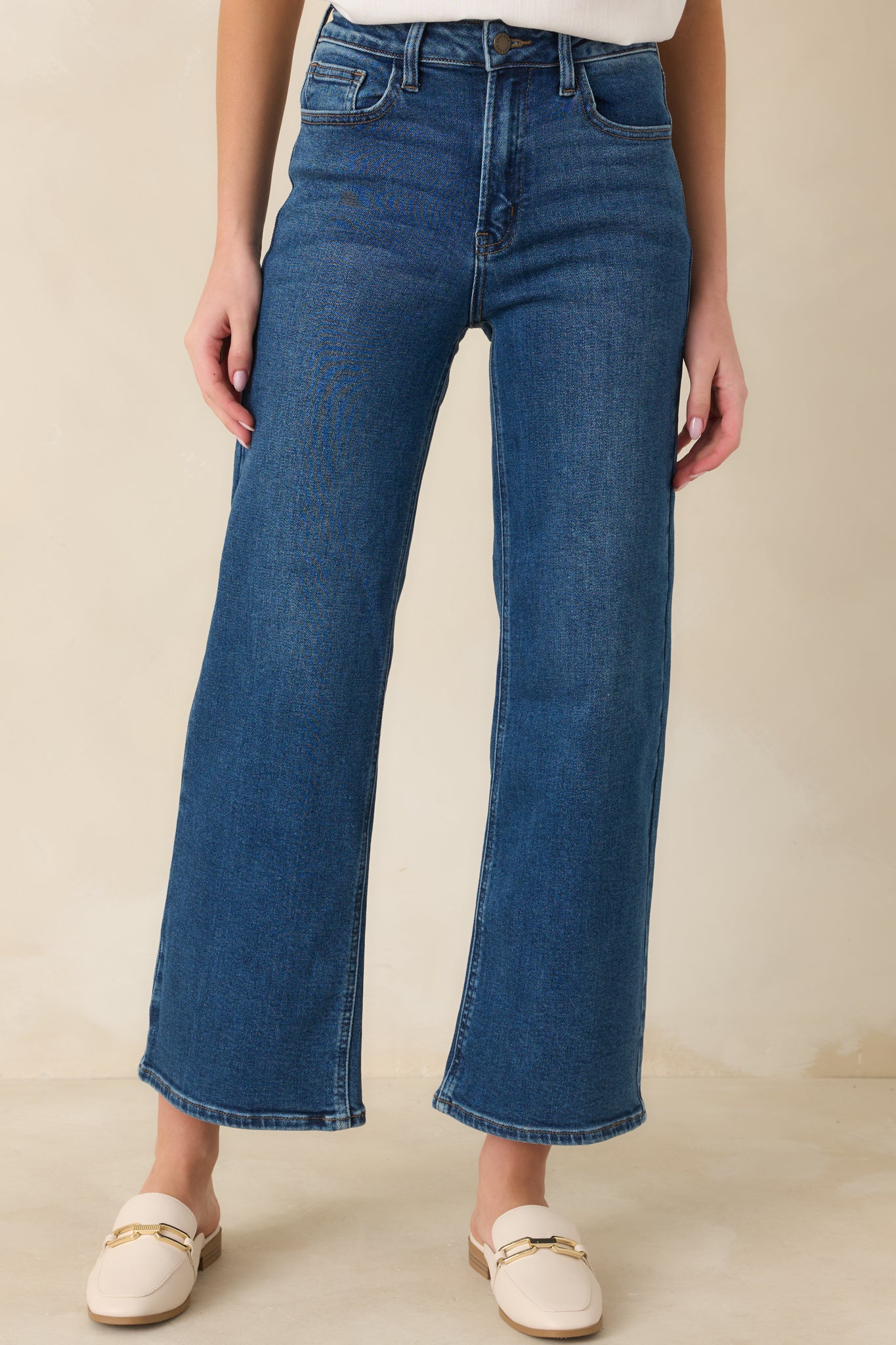 Close cropped angle of dark wash jeans highlighting the front pockets and subtle stitching details.