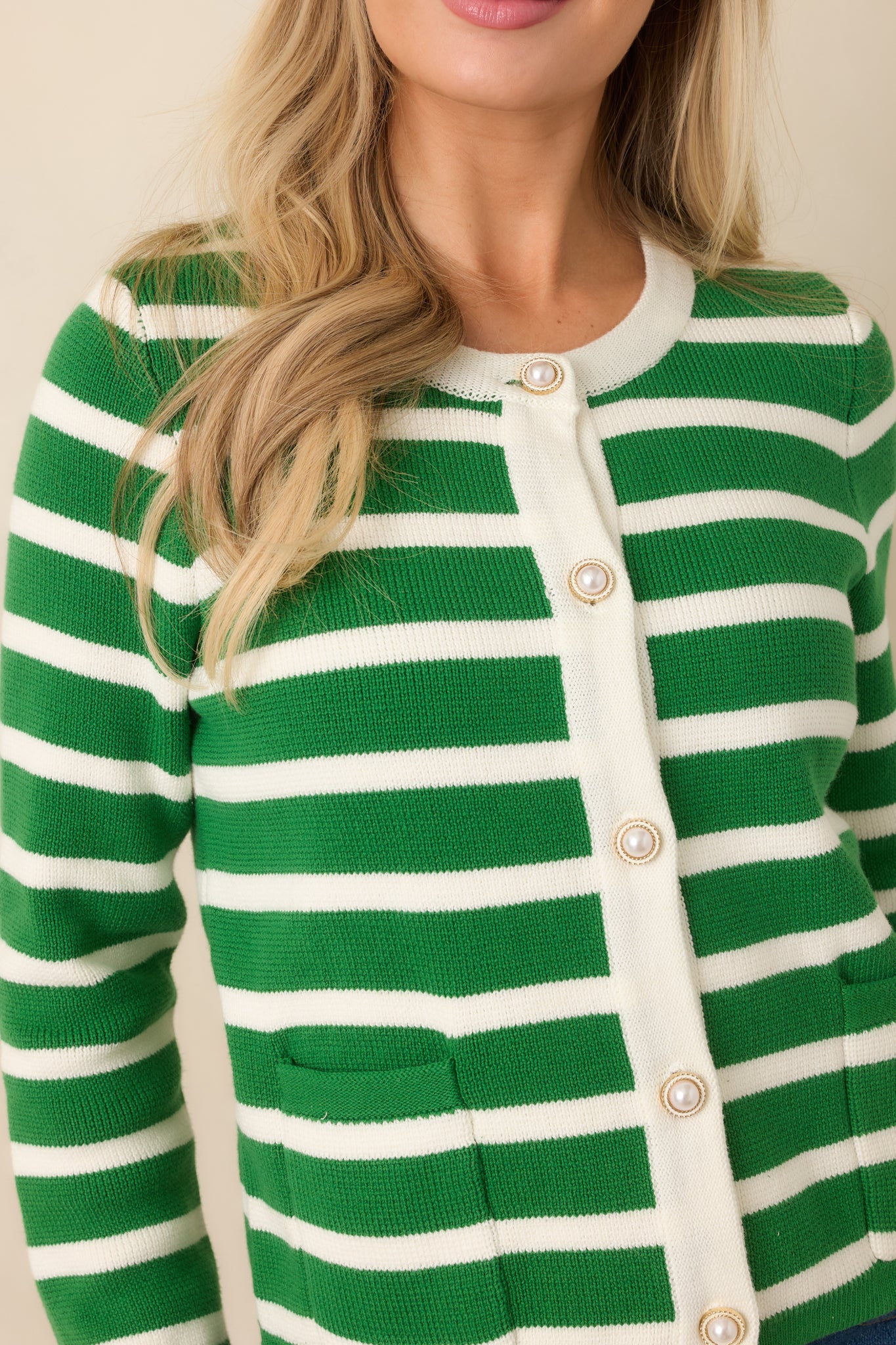 Close-up of the green striped cardigan showing the gold-tone buttons and stripe detailing.