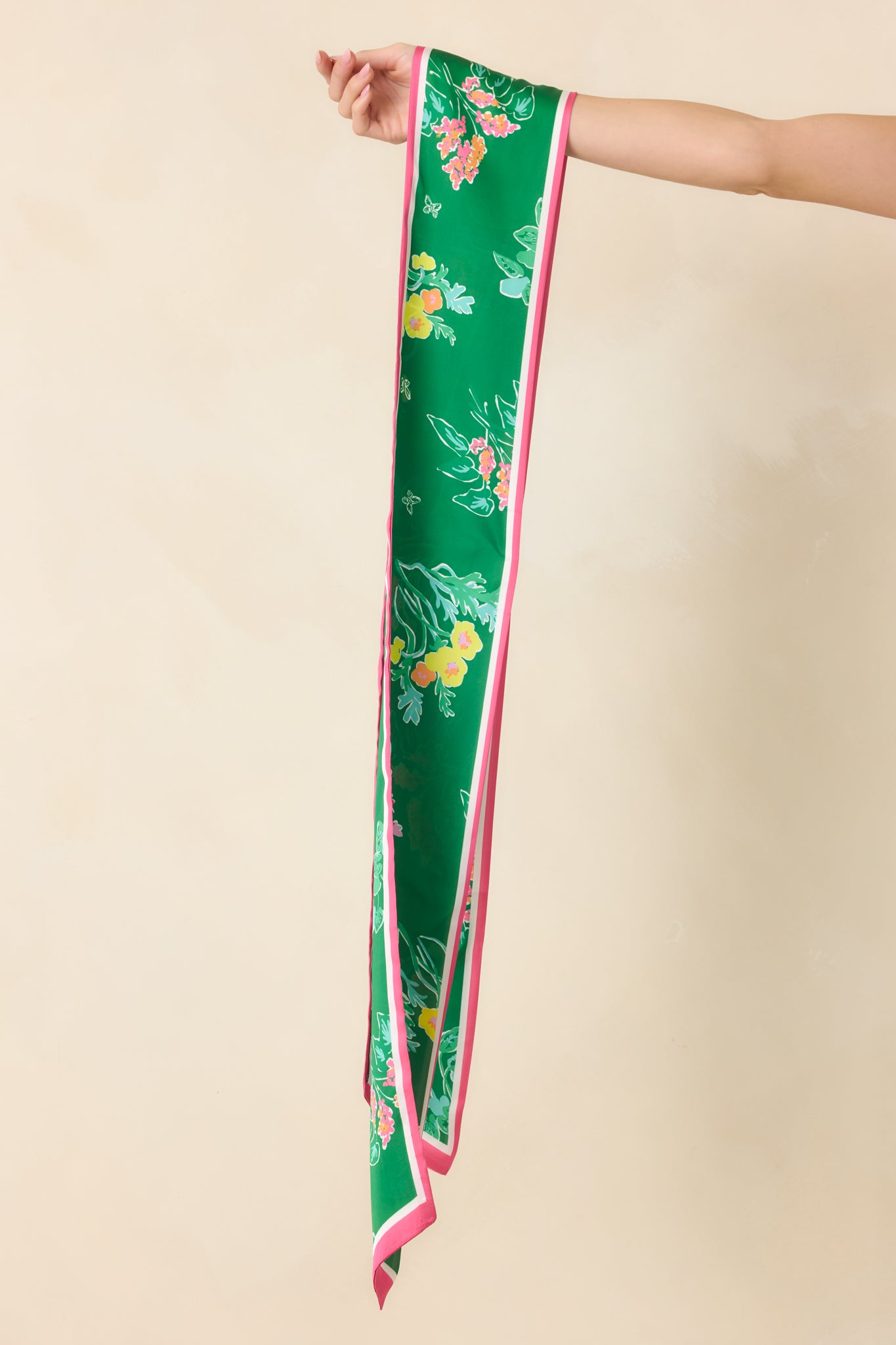Full view of green slim scarf with scattered floral pattern and vibrant pink edging, showcasing its soft, lightweight texture.