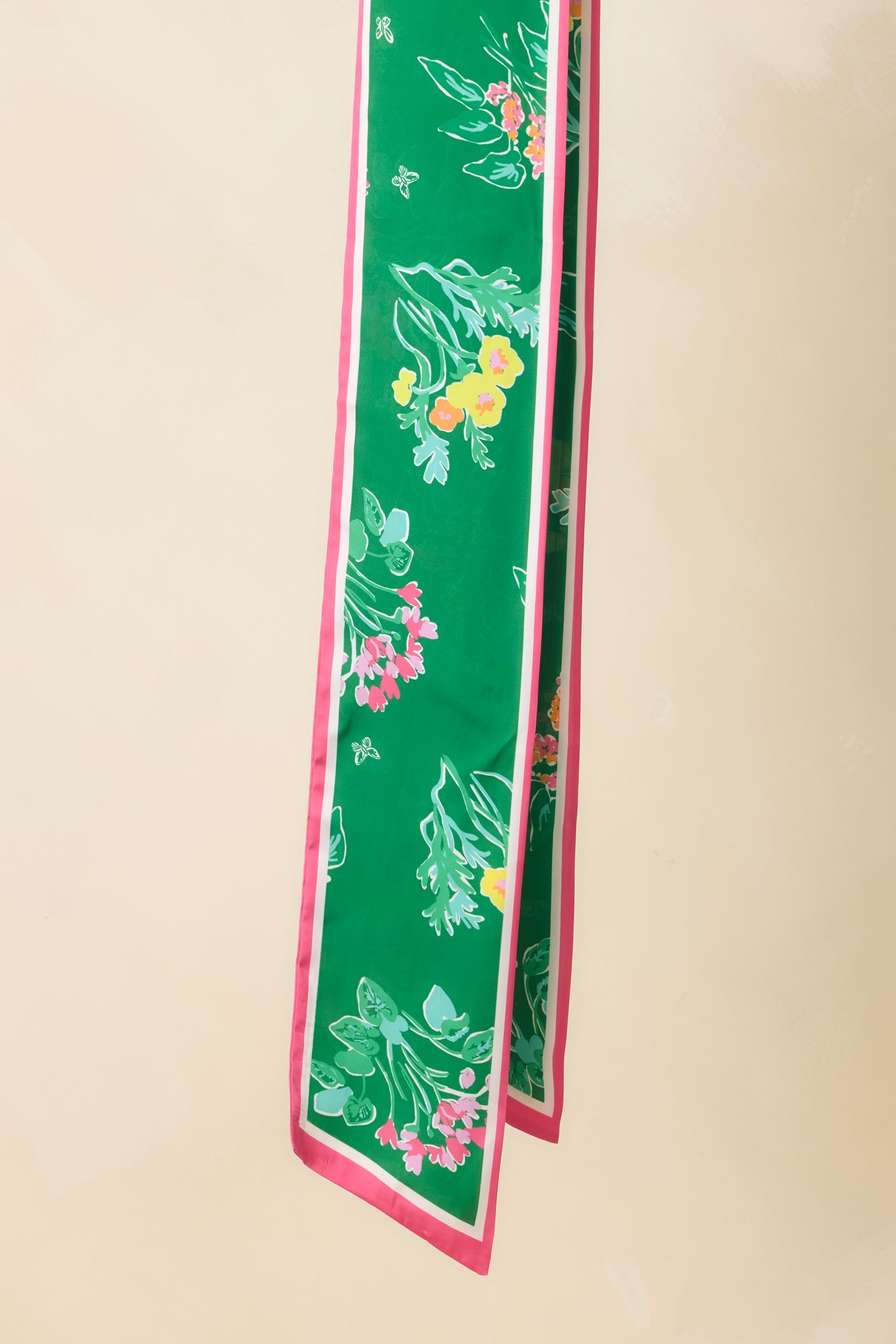 Detailed close-up of the green scarf showing floral pattern intricacy and the crisp pink border along the edge.