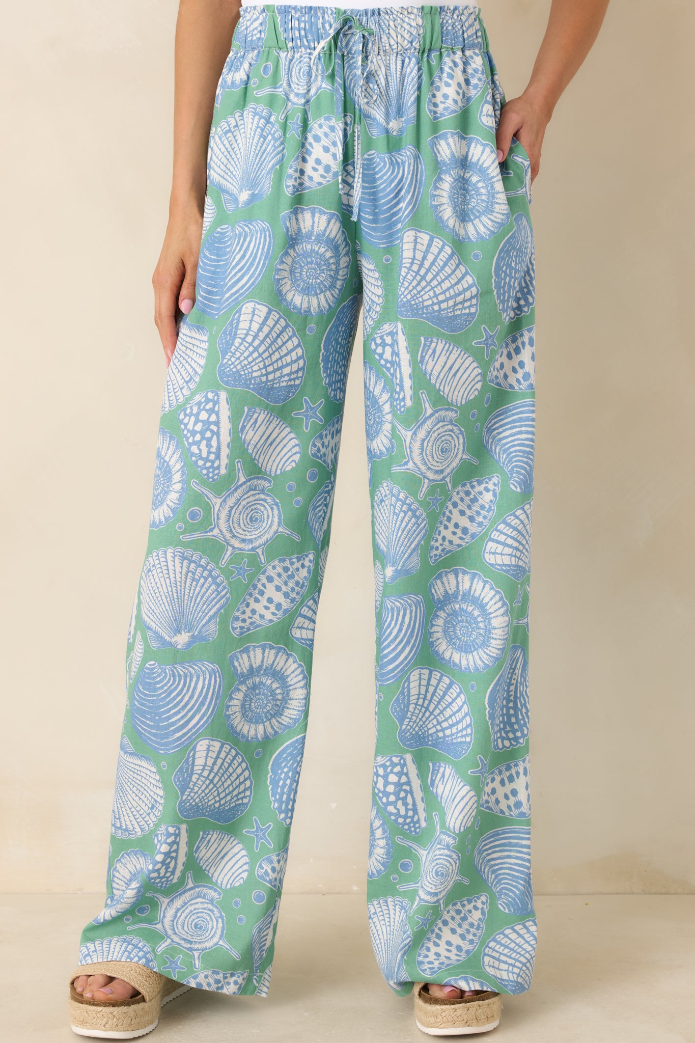 Front cropped view highlighting the oversized shell print in blue and ivory against the green background.