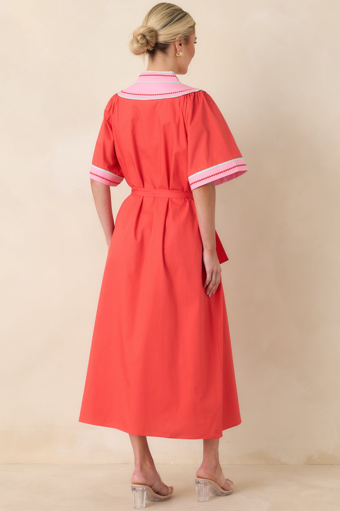 Rear view of the poppy red midi dress showing the clean silhouette, flutter sleeves, and removable self-tie belt defining the waistline.