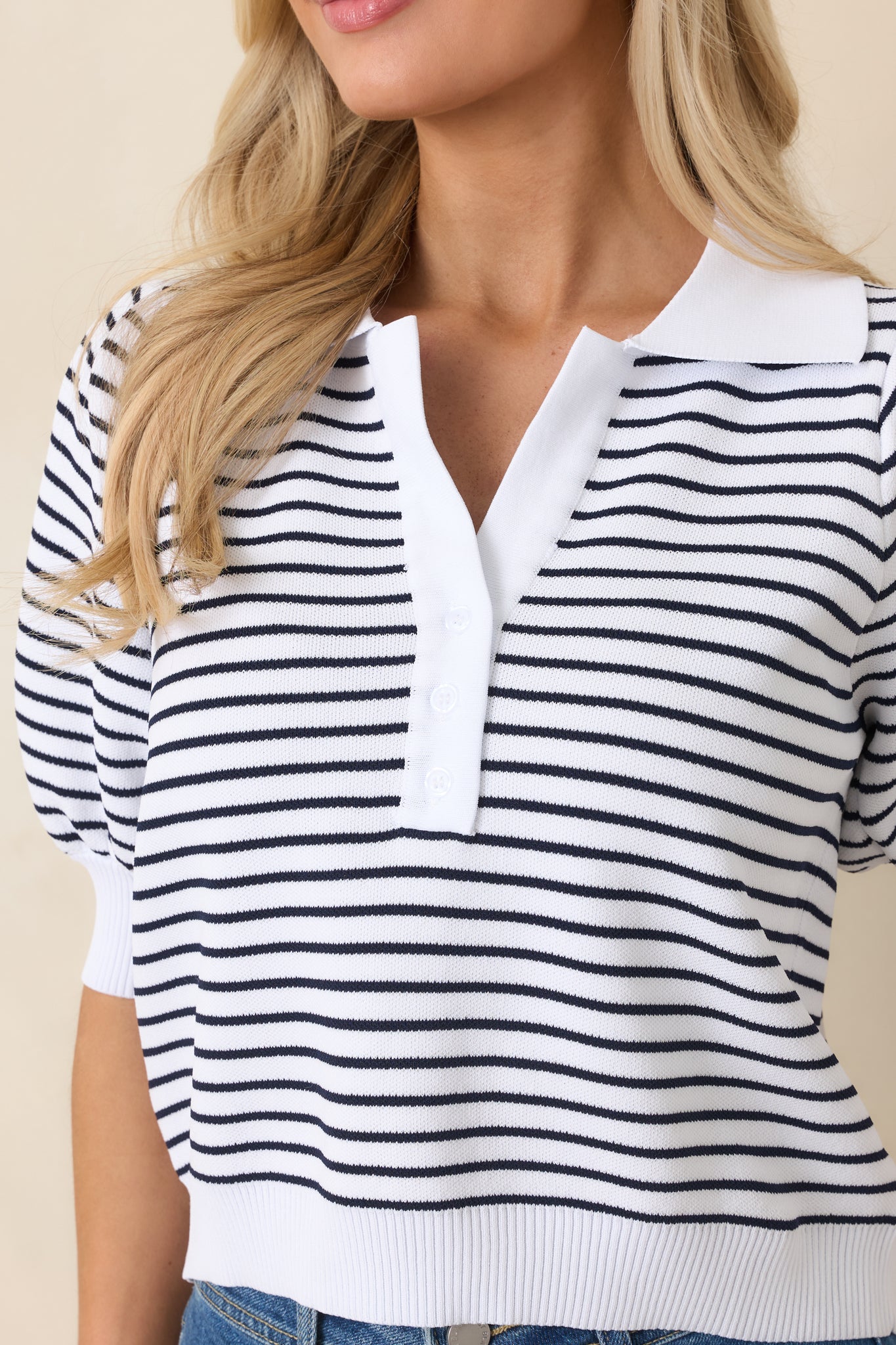 Close-up of the knit fabric, ribbed cuffs and hem, and collar with partial button placket for refined texture.